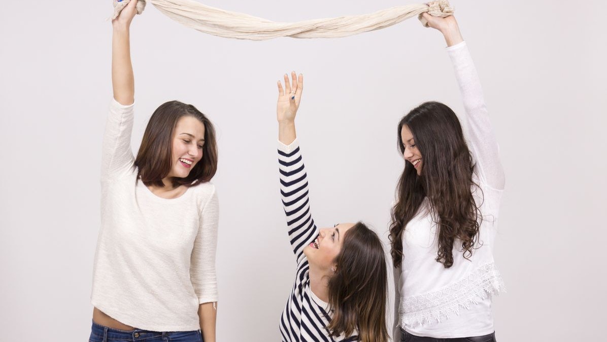 short girl trying to reach taller girls scarf