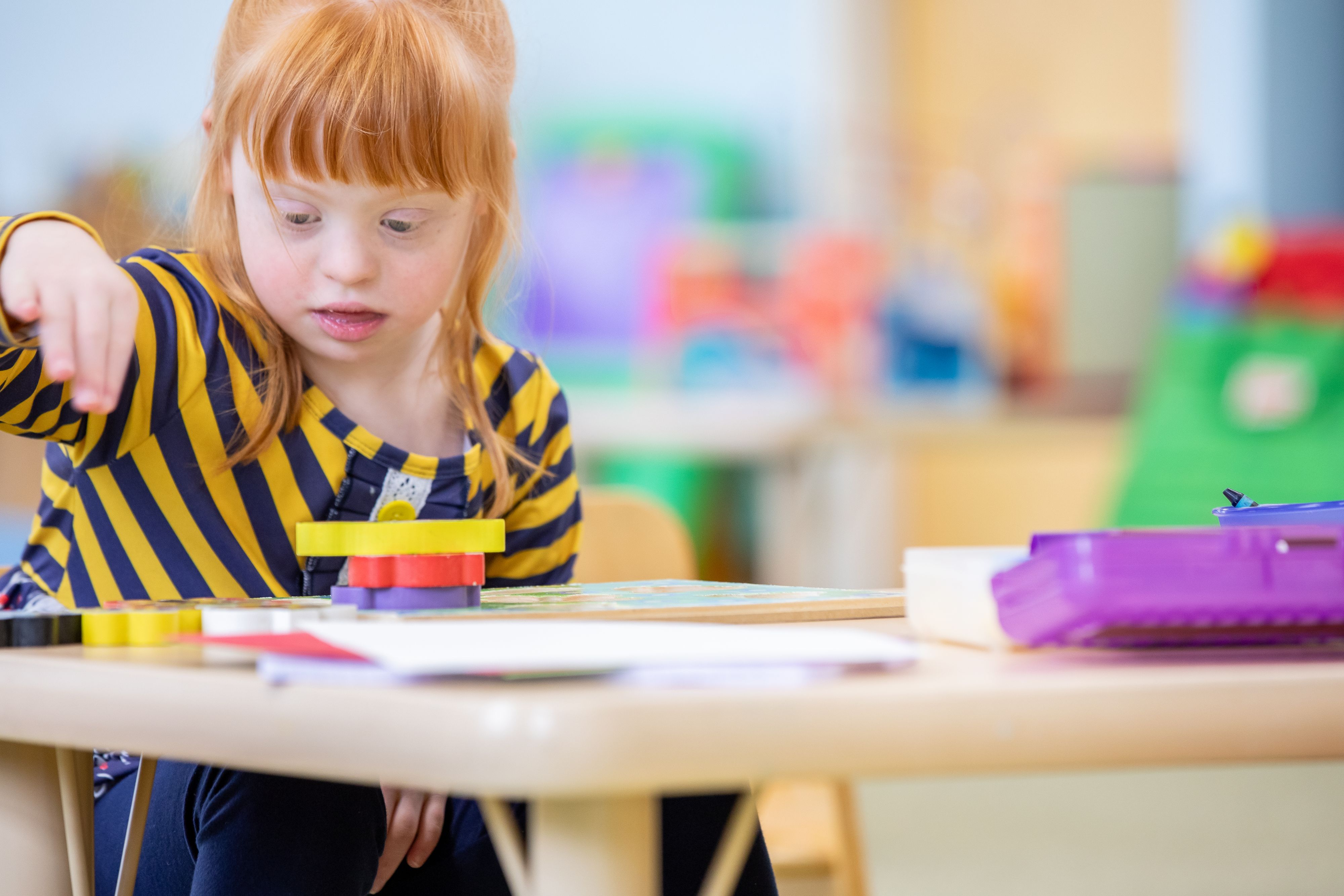 Ein Kind mit Down-Syndrom spielt im Kindergarten – viele Familien kämpfen aktuell mit gekürzter Unterstützung.