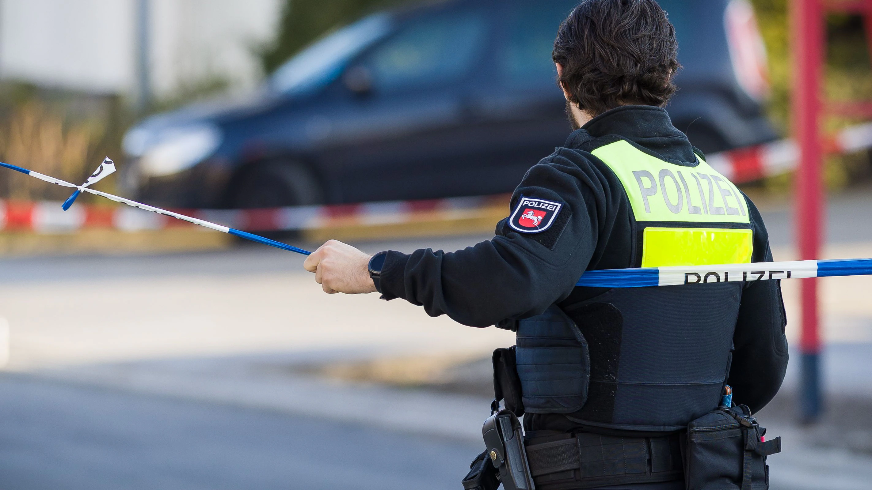 23 March 2026, Lower Saxony, Barsinghausen: A police officer blocks a road in front of a detached house in the Hanover region. A 49-year-old man is said to have fatally injured a 38-year-old woman in Barsinghausen near Hanover and critically injured their 13-year-old daughter. Photo: Moritz Frankenberg/dpa
