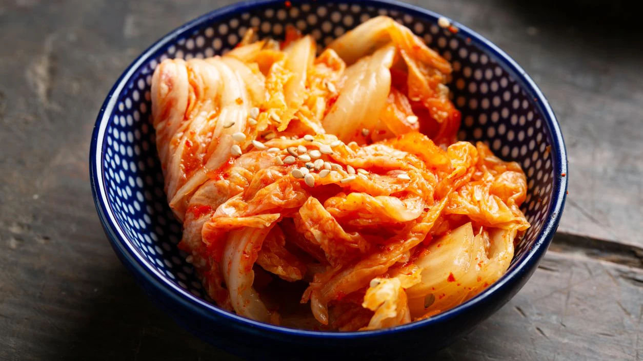 Korean fermented food-Kimchee in a bowl on wooden background, sprinkled with some sesame seeds