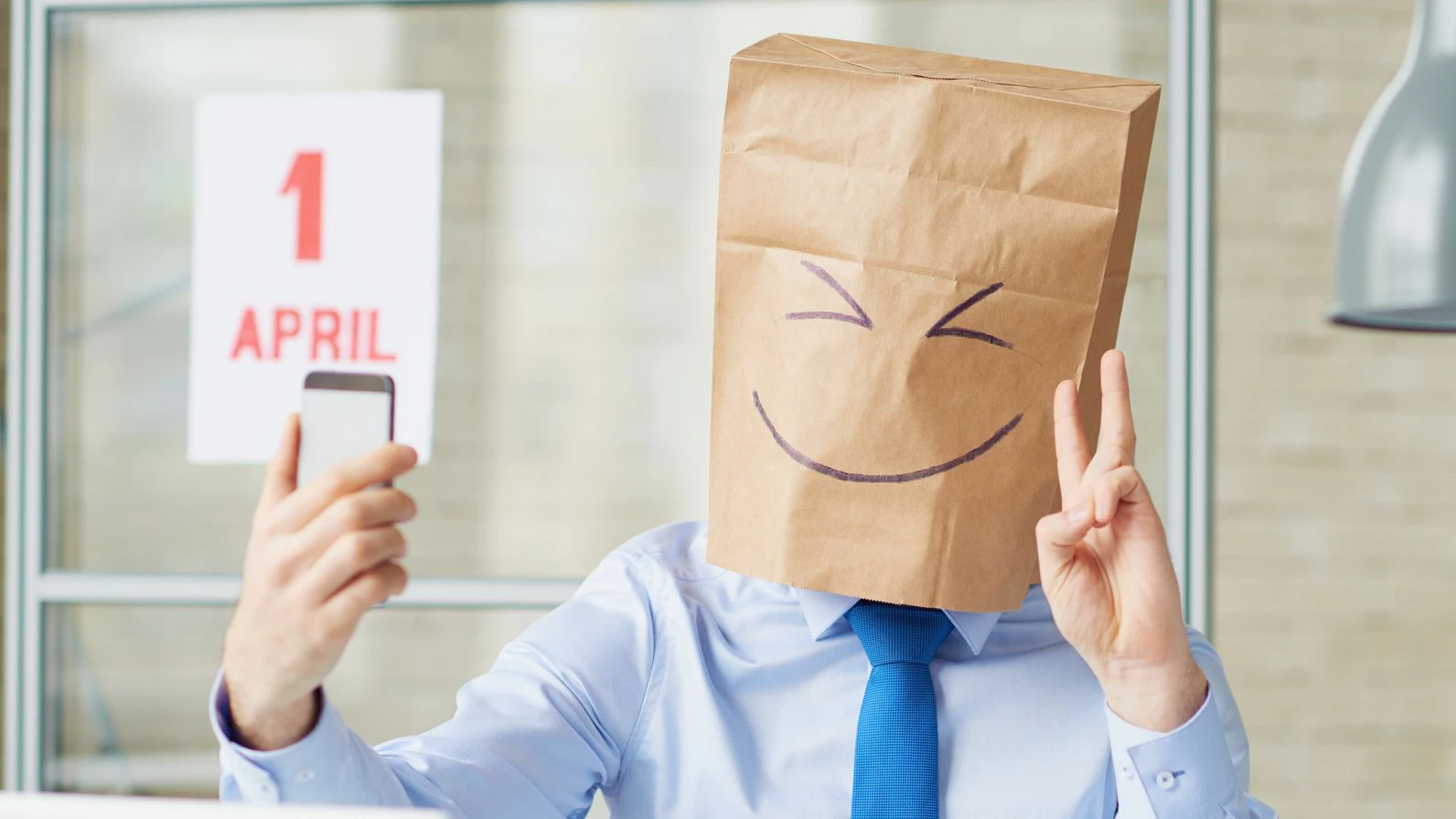 Businessman in paper bag making selfie at office