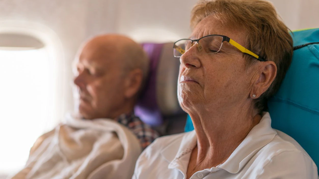 active senior woman and man travelling by air sleeping during long haul flight