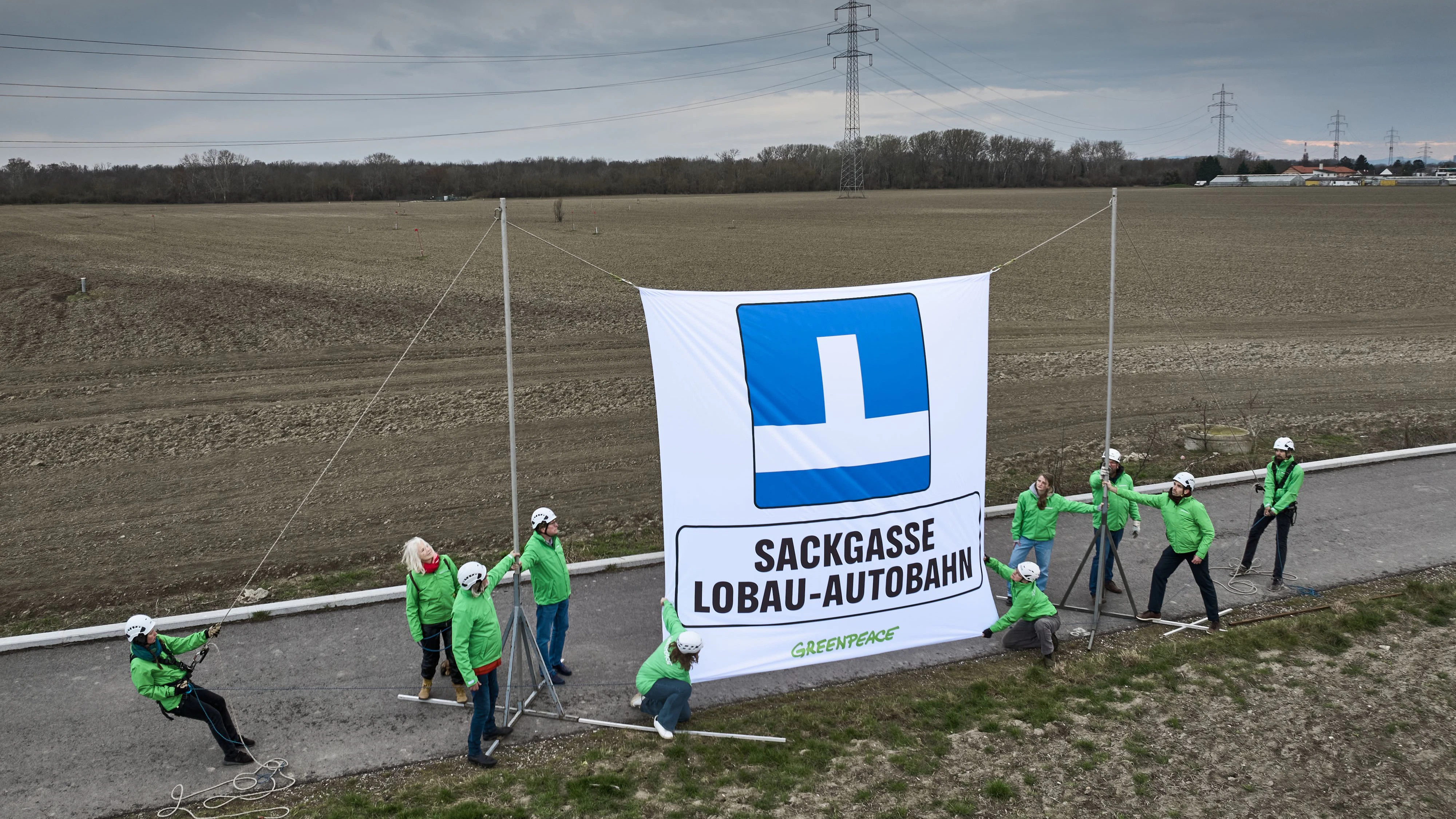 Greenpeace-Aktivisten imt einem Sackgassenschild am Ende der Trasse der geplanten Lobau-Autobahn.