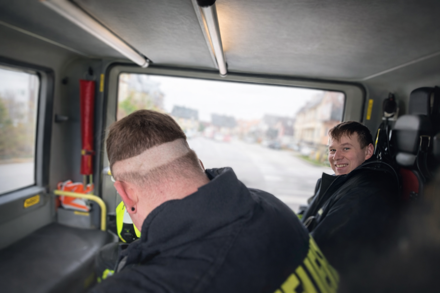 Feuerwehr-Alltag mit Humor: Während vorne die Straße wartet, sorgt hinten ein missglückter Haarschnitt für Lacher.