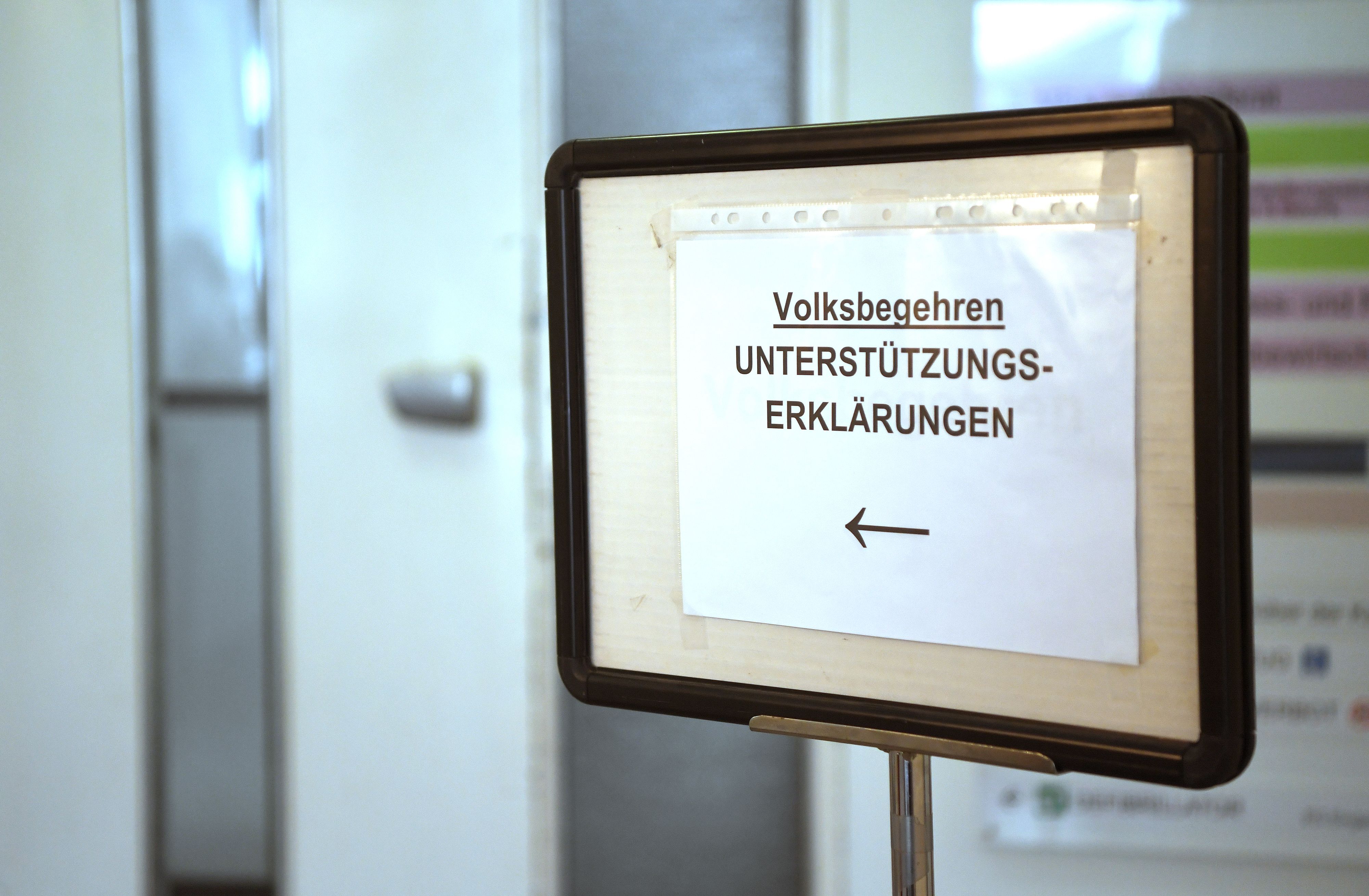 Ein Schild weist den Weg zu einem Servicedesk an dem Unterstützungserklärungen für Volksbegehren abgegeben werden können.