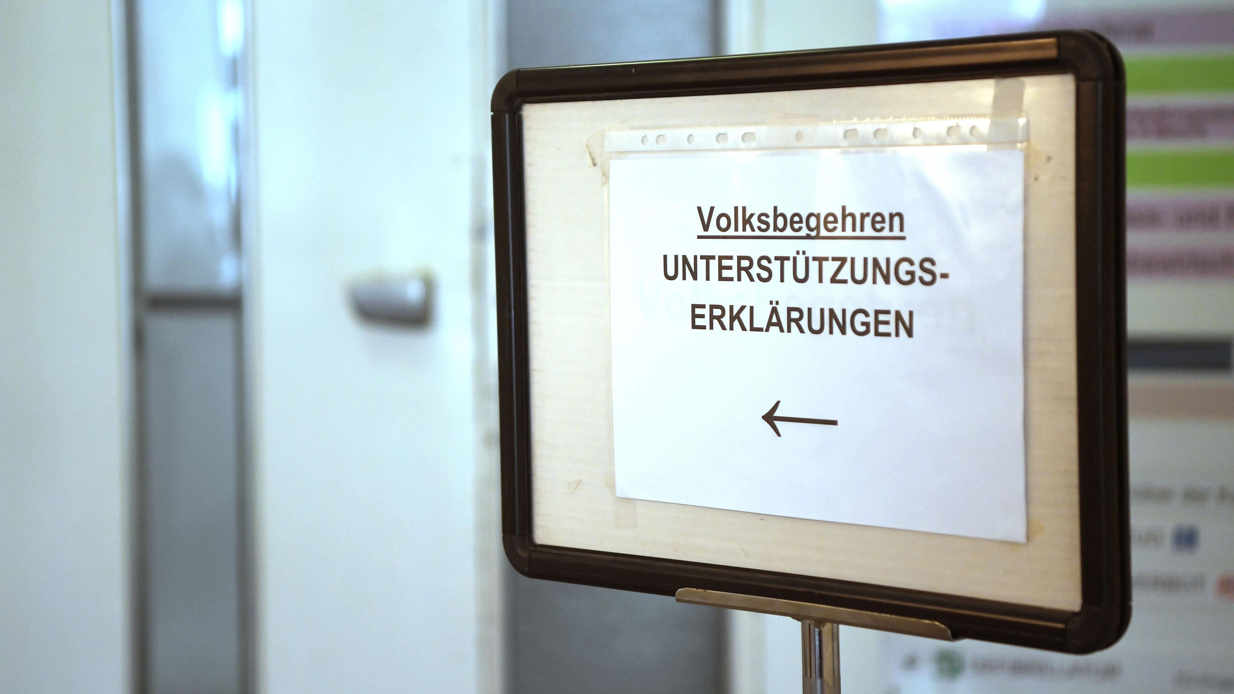 Ein Schild weist den Weg zu einem Servicedesk an dem Unterstützungserklärungen für Volksbegehren abgegeben werden können.