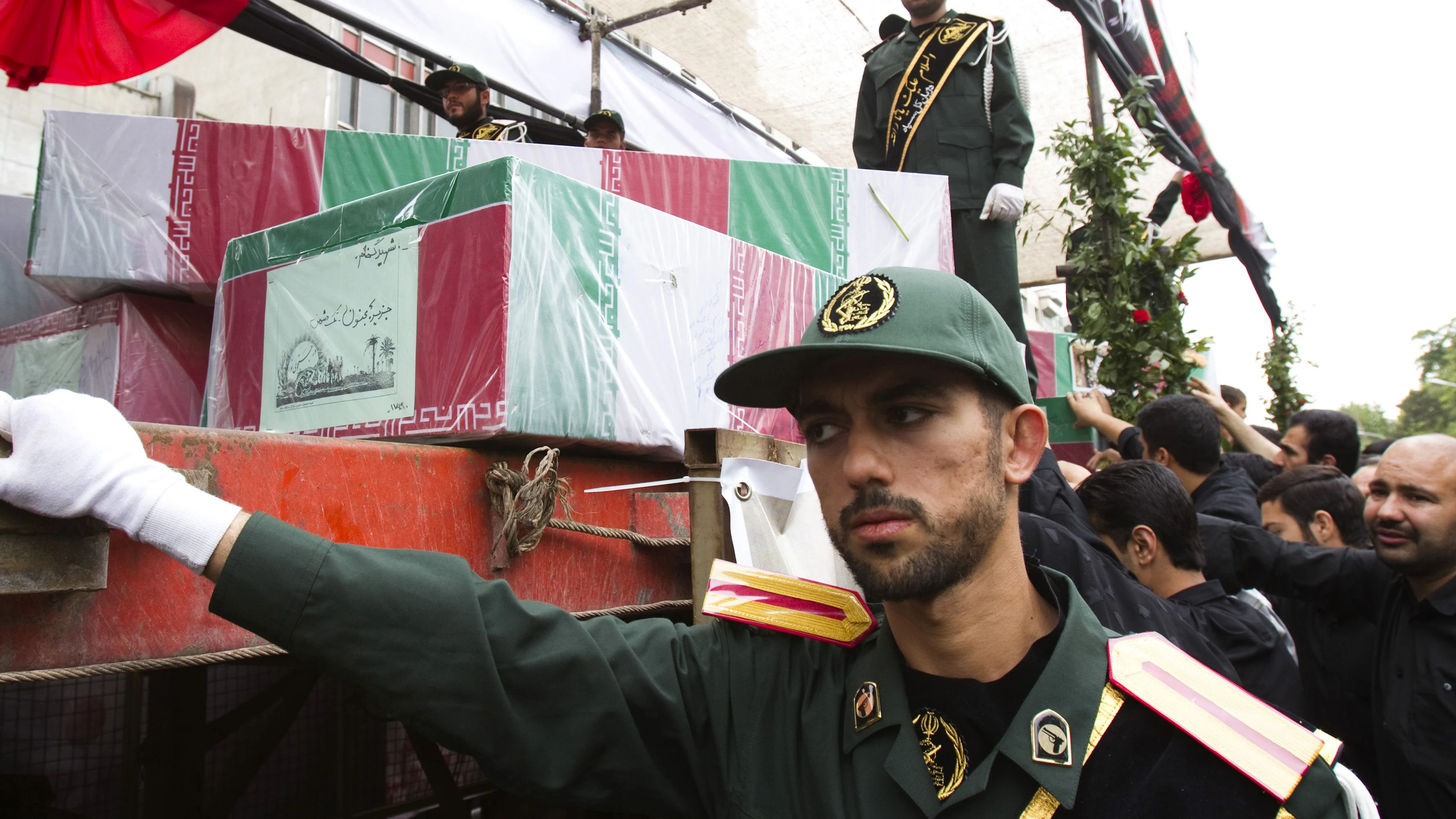 EDITORS' NOTE: Reuters and other foreign media are subject to Iranian restrictions on their ability to report, film or take pictures in Tehran.   A member of Iran's Revolutionary guard stands near the coffins of recently recovered bodies of fallen soldiers of the Iran-Iraq war (1980-1988), in Tehran May 14, 2010. REUTERS/Raheb Homavandi (IRAN)