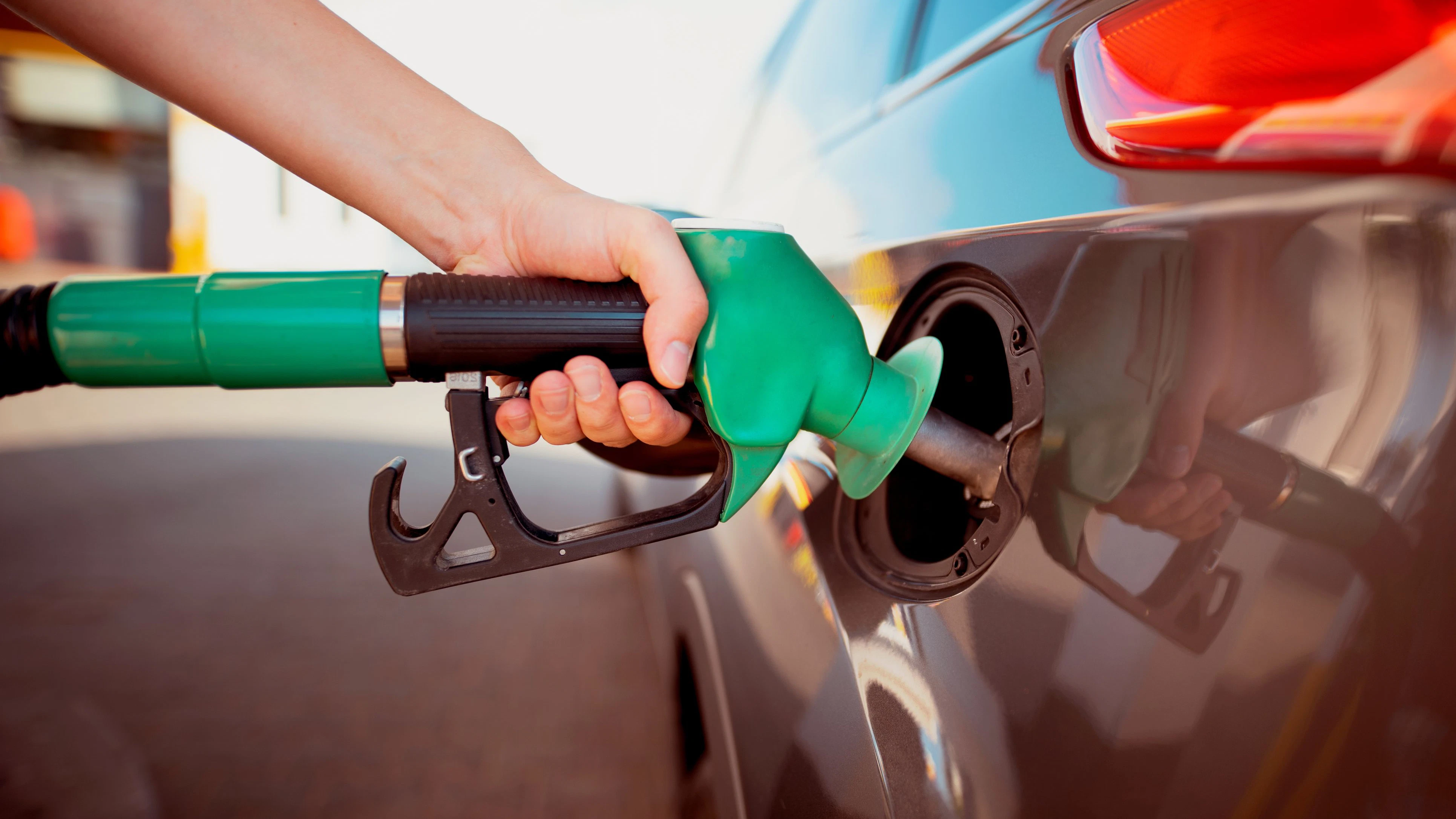 Pumping gas at gas pump. Closeup of man pumping gasoline fuel in car at gas station.