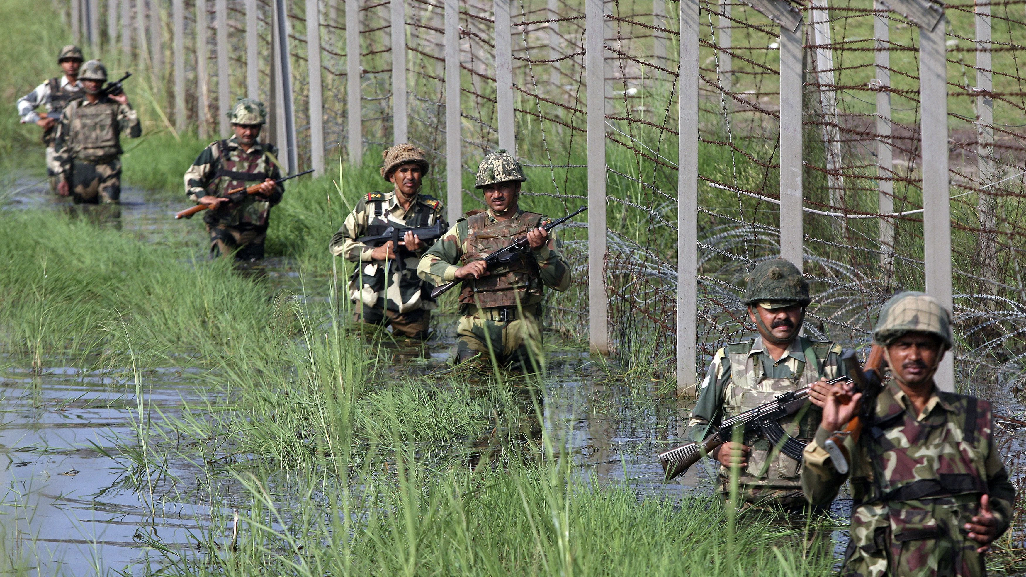 Indian Border Security Force (BSF) soldiers patrol the fenced border with Pakistan as they wade through floodwaters on the outskirts of Jammu September 13, 2014. Residents of revolt-torn Indian Kashmir turned their wrath on state administrators for failing to provide them with succour after the worst flooding in over a century, angrily dumping food parcels into gutters. REUTERS/Mukesh Gupta (INDIAN-ADMINISTERED KASHMIR - Tags: DISASTER MILITARY ENVIRONMENT)
