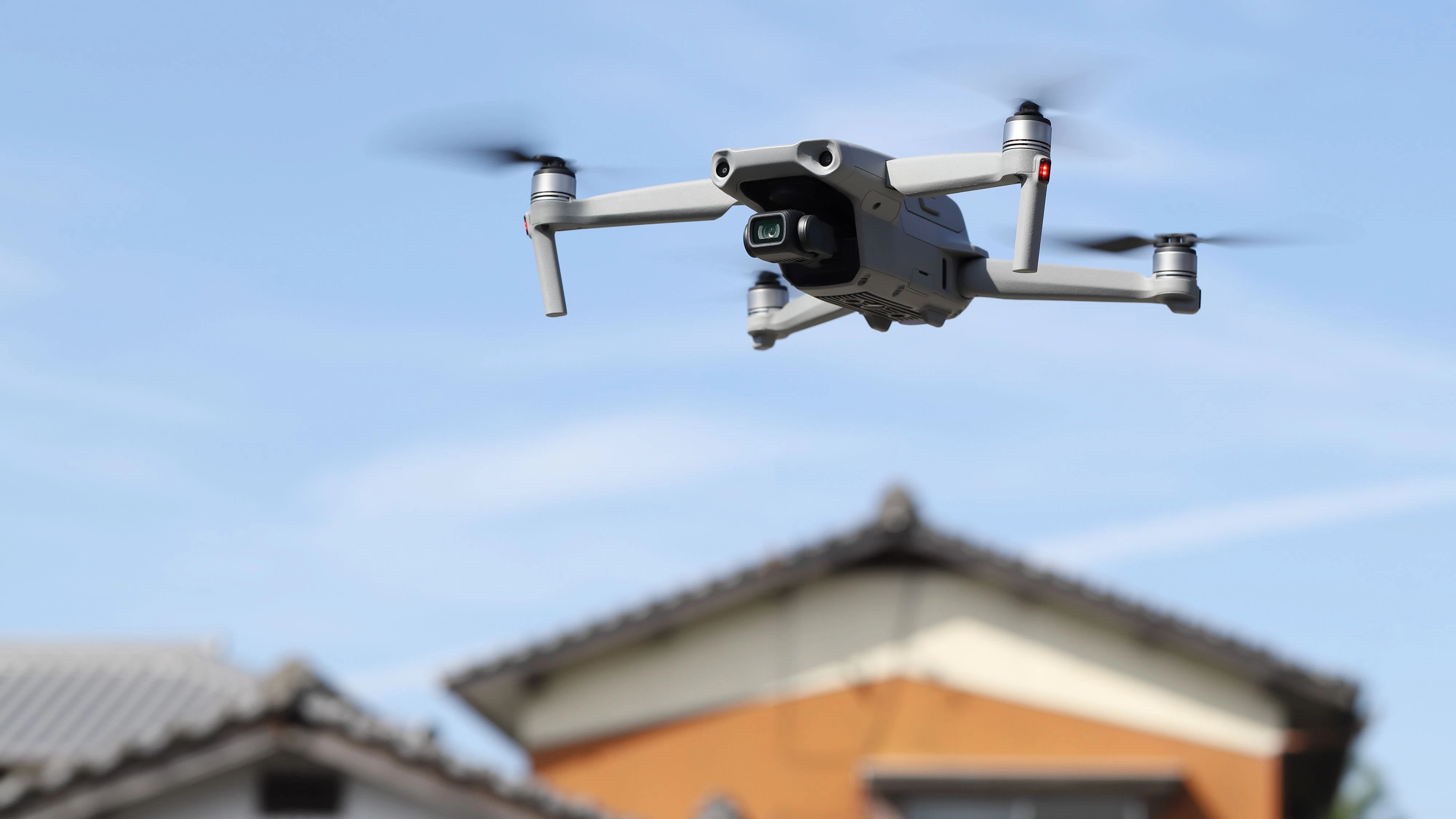 Kagawa, Japan - Oct 30, 2021: Flying radio controlled DJI Mavic air2 quadcopter drone with aerial photo and video camera against the blue sky with  private house