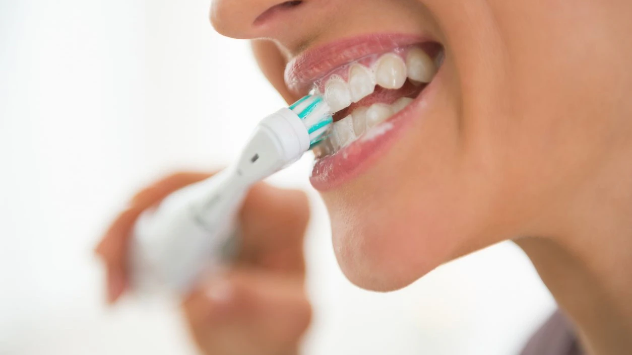 Closeup on young woman brushing teeth