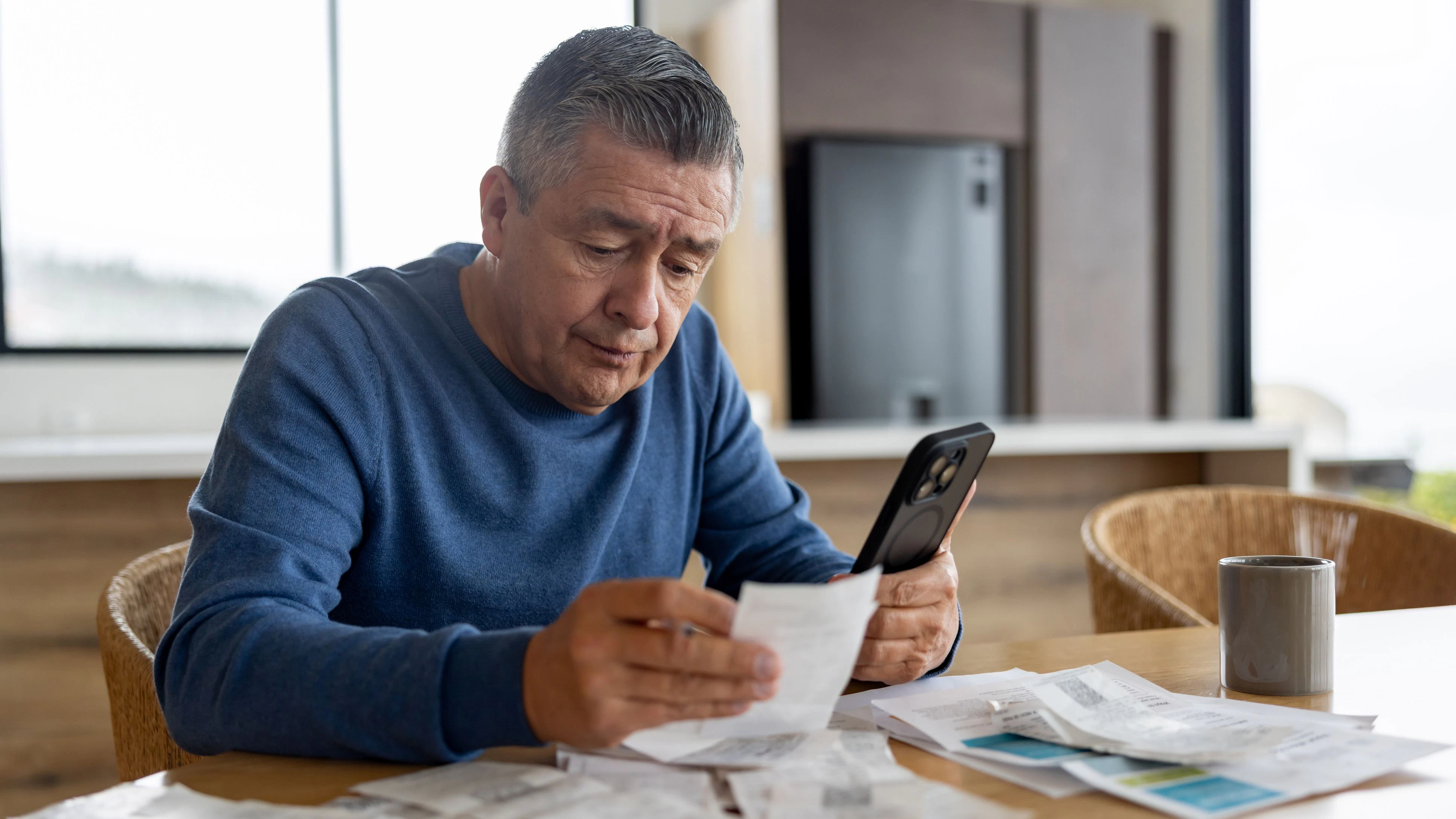 Portrait of a retired Latin American man at home paying bills online and looking worried - home finances concepts
