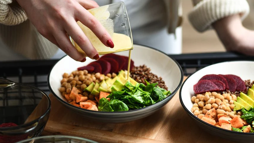 Female Preparing Aesthetically Pleasing Salad Bowls Adding Dressing on Top To Tie Flavors Together