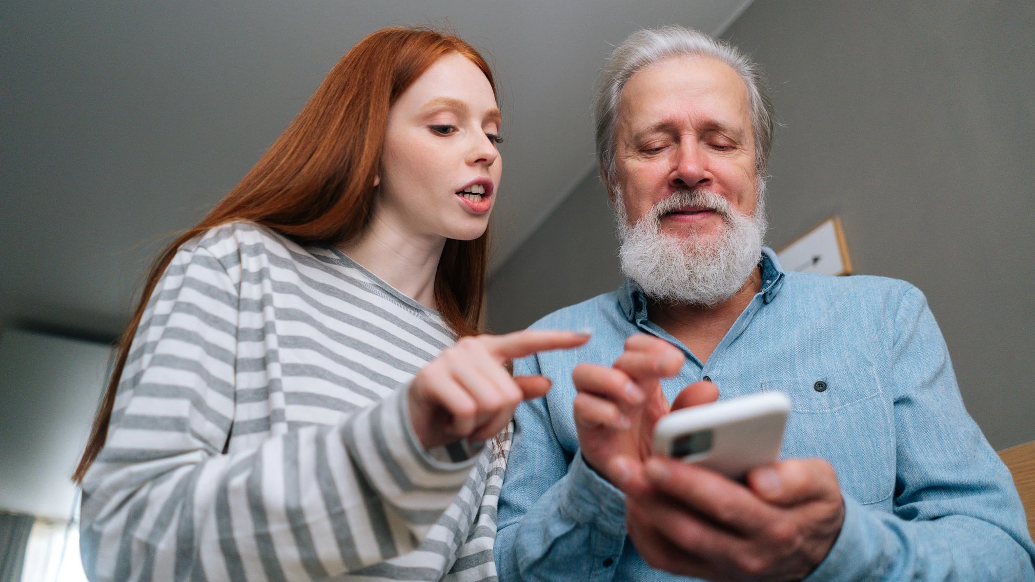 Jugendliche erklärt älterem Herrn, was mit dem Smartphone alles geht.