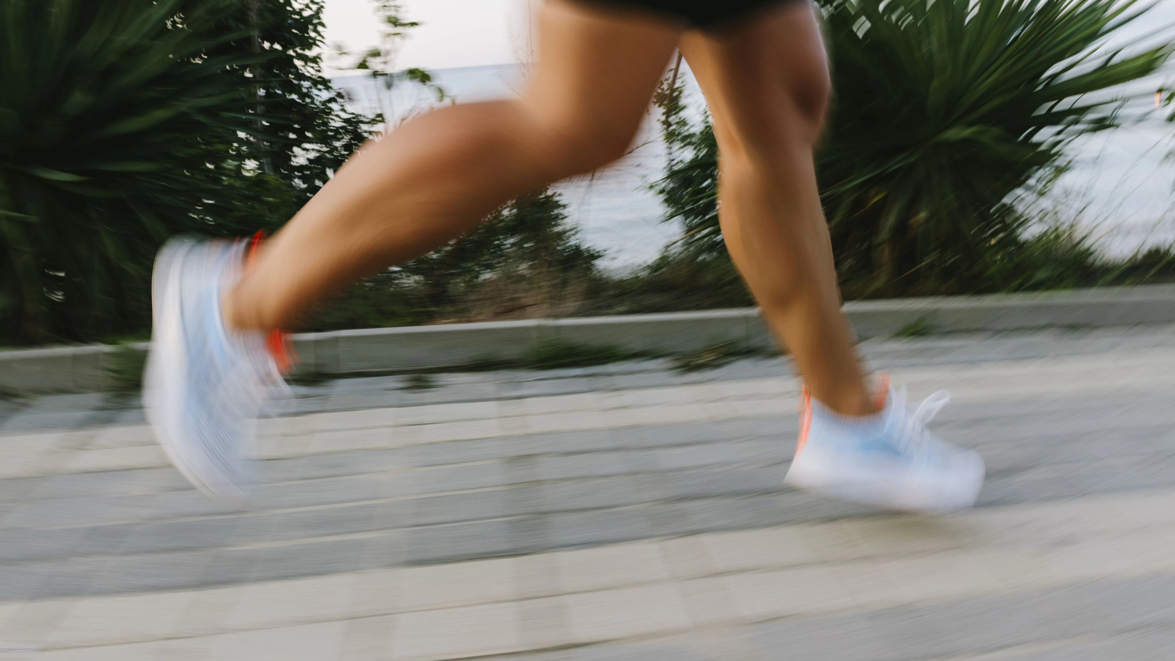 Woman wearing white shoes running on footpath