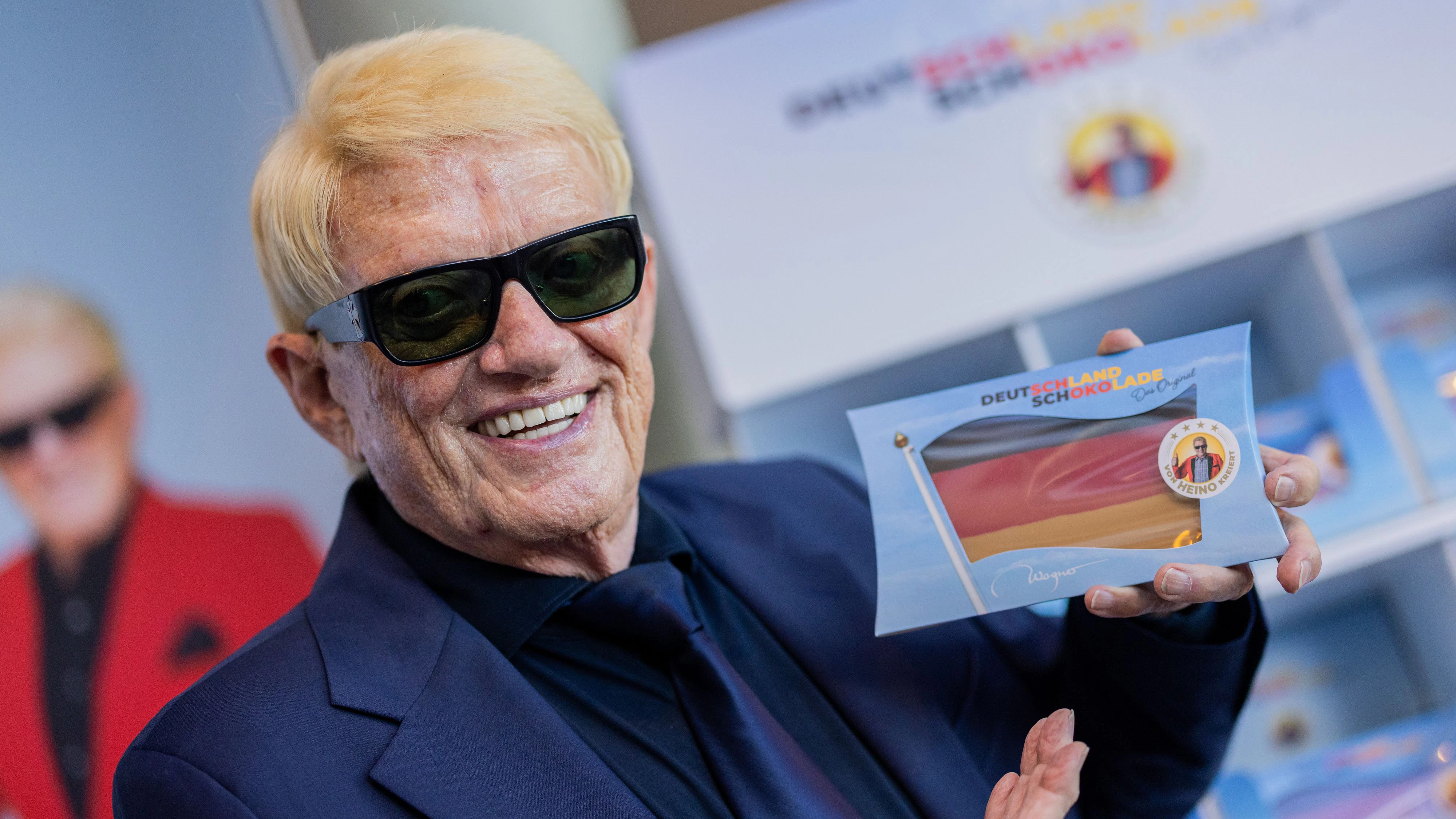 29 August 2025, North Rhine-Westphalia, Cologne: Pop singer Heino presents his "Germany Chocolate" (manufacturer: Wagner) at the Chocolate Museum. The chocolate in the national colors consists of dark, cherry and caramel chocolate. Photo: Rolf Vennenbernd/dpa
