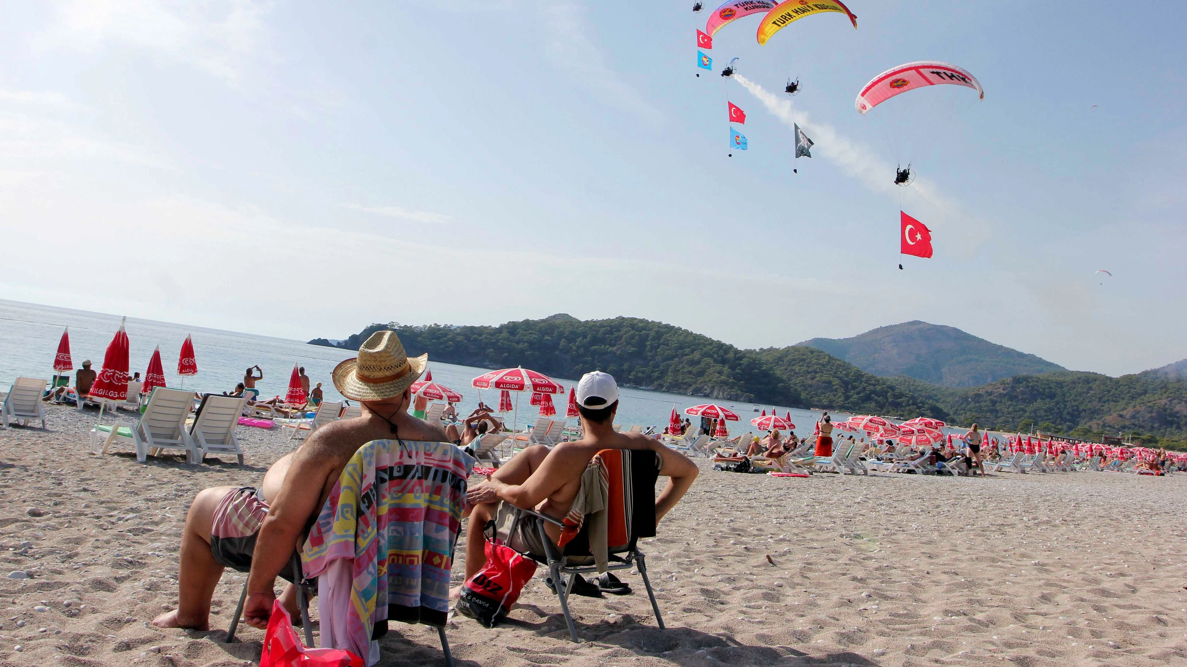 Local and foreign tourists watch International Oludeniz Air Games as they enjoy the sunny weather on a beach in Fethiye in Mugla province, Turkey October 11, 2016. Picture taken October 11, 2016. REUTERS/Kenan Gurbuz