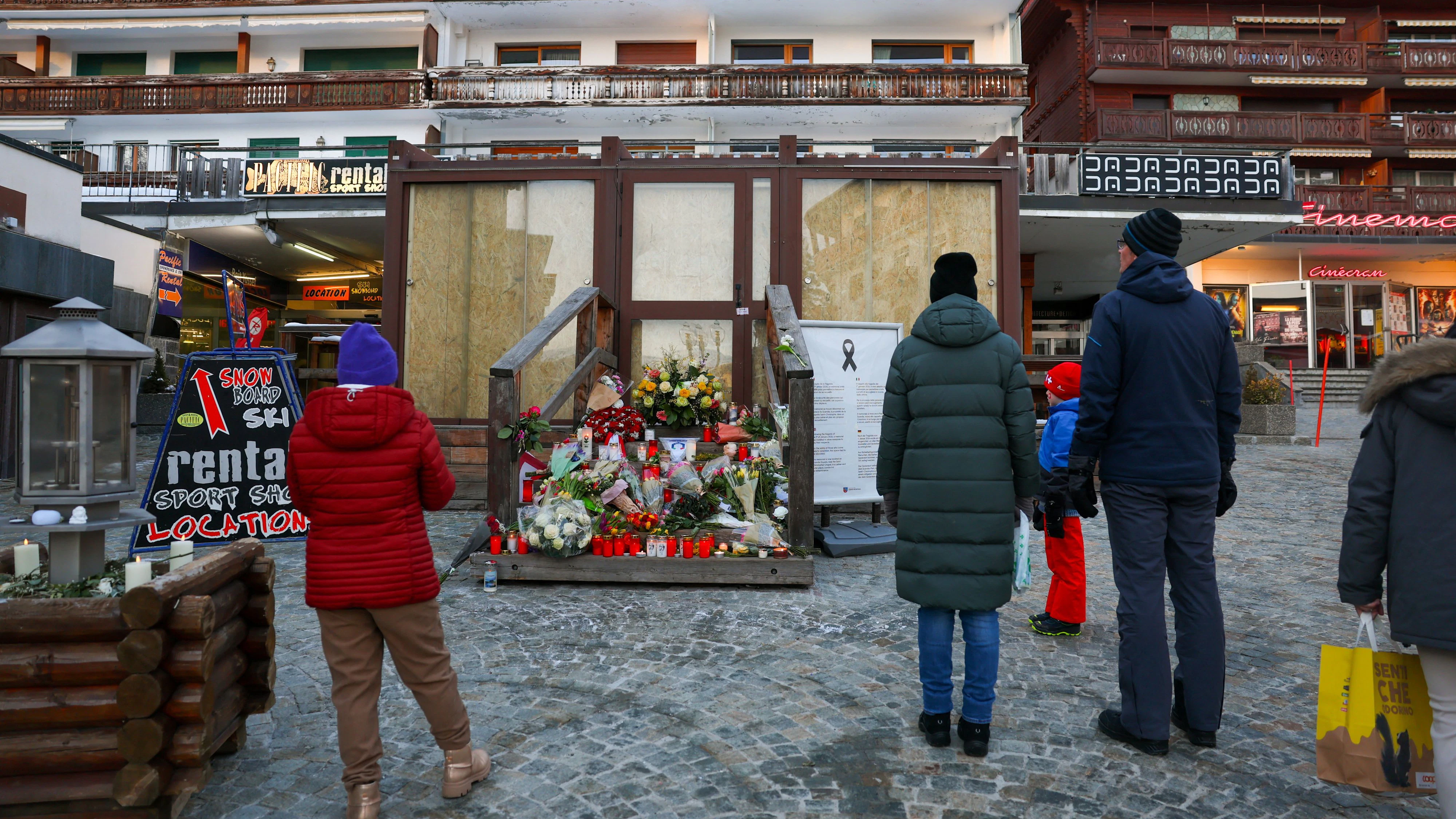 People stand by a makeshift memorial outside the "Le Constellation bar" almost a month after a deadly fire during a New Year's Eve party, in the upscale ski resort of Crans-Montana, Switzerland, January 31, 2026. REUTERS/Denis Balibouse  