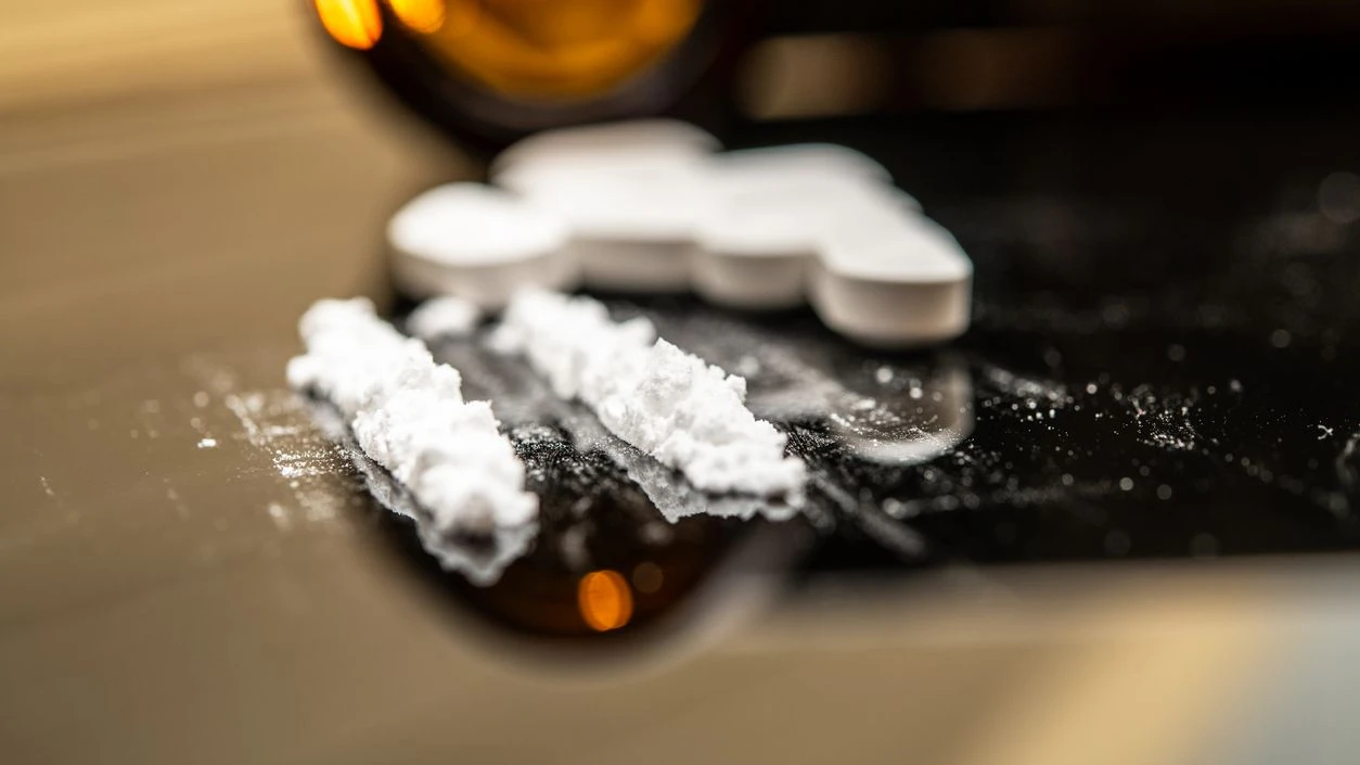 Fentanyl powder and prescription pills scattered on a reflective surface, illustrating the serious impacts of opioid misuse and prescription drug abuse in contemporary society.
