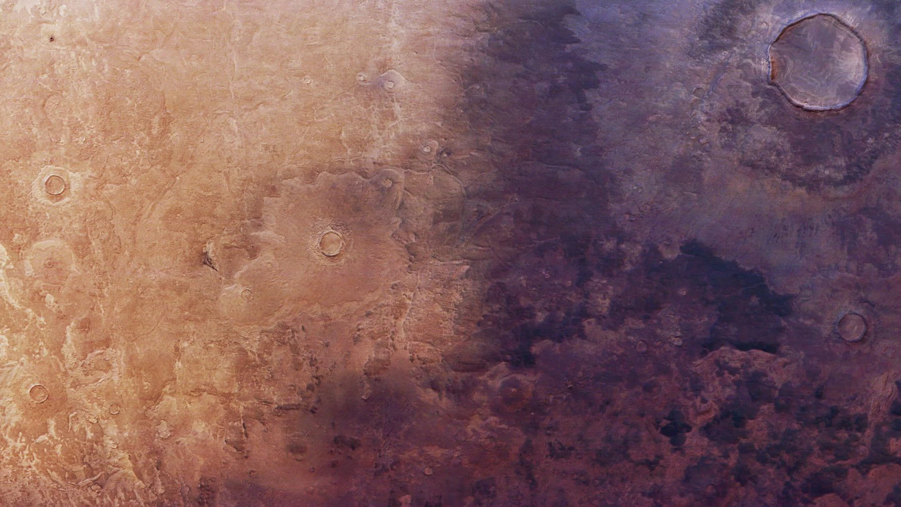 Ein Weitblick auf die Marsoberfläche aus der Vogelperspektive. Die Landschaft ist in zwei kontrastreiche Hälften geteilt: Die linke Seite ist heller, sandbeige mit schwachen Rippen und Rissen, während die rechte Seite dunkler, rotbraun und stärker mit Kratern übersät ist. Norden ist in dieser Mars-Express-Aufnahme rechts. Die Bodenauflösung des Originalbildes beträgt etwa 17 m/Pixel, und der Bildmittelpunkt liegt etwa bei den Mars-Koordinaten 43° N/102° O.