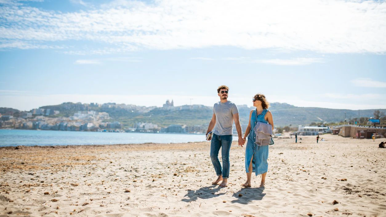Heterosexual couple walking on the beach and holding hands