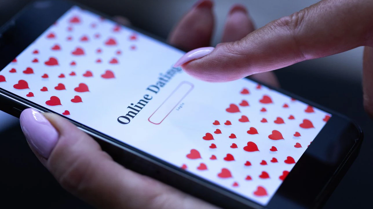 Online dating, internet dating site, user login, red hearts. Hand of a woman holding smartphone. Love, affair, romantic feelings, affection, relationship, partner search, ghosting, happiness, communication.