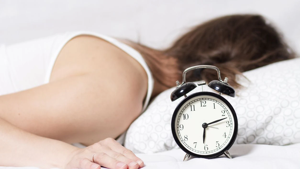 young woman does not hear ringing of an alarm clock in the morning. The girl does not want to get up early in the morning to work