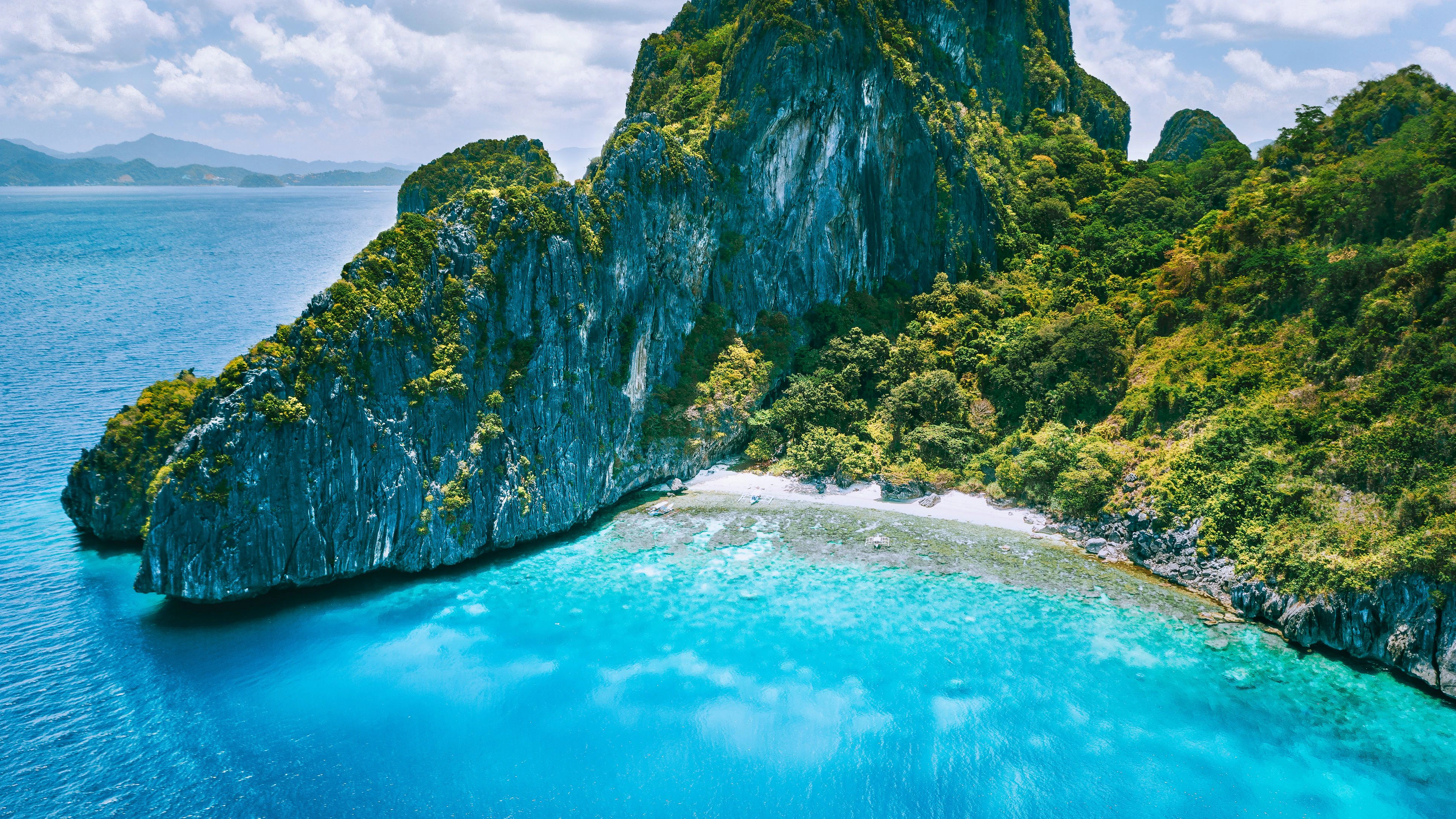 El Nido, Palawan. Aerial drone view of tropical Entalula Island. Huge steep rocks cliffs mountains with blue bay and beautiful intact coral reef. Island hopping tour trip.