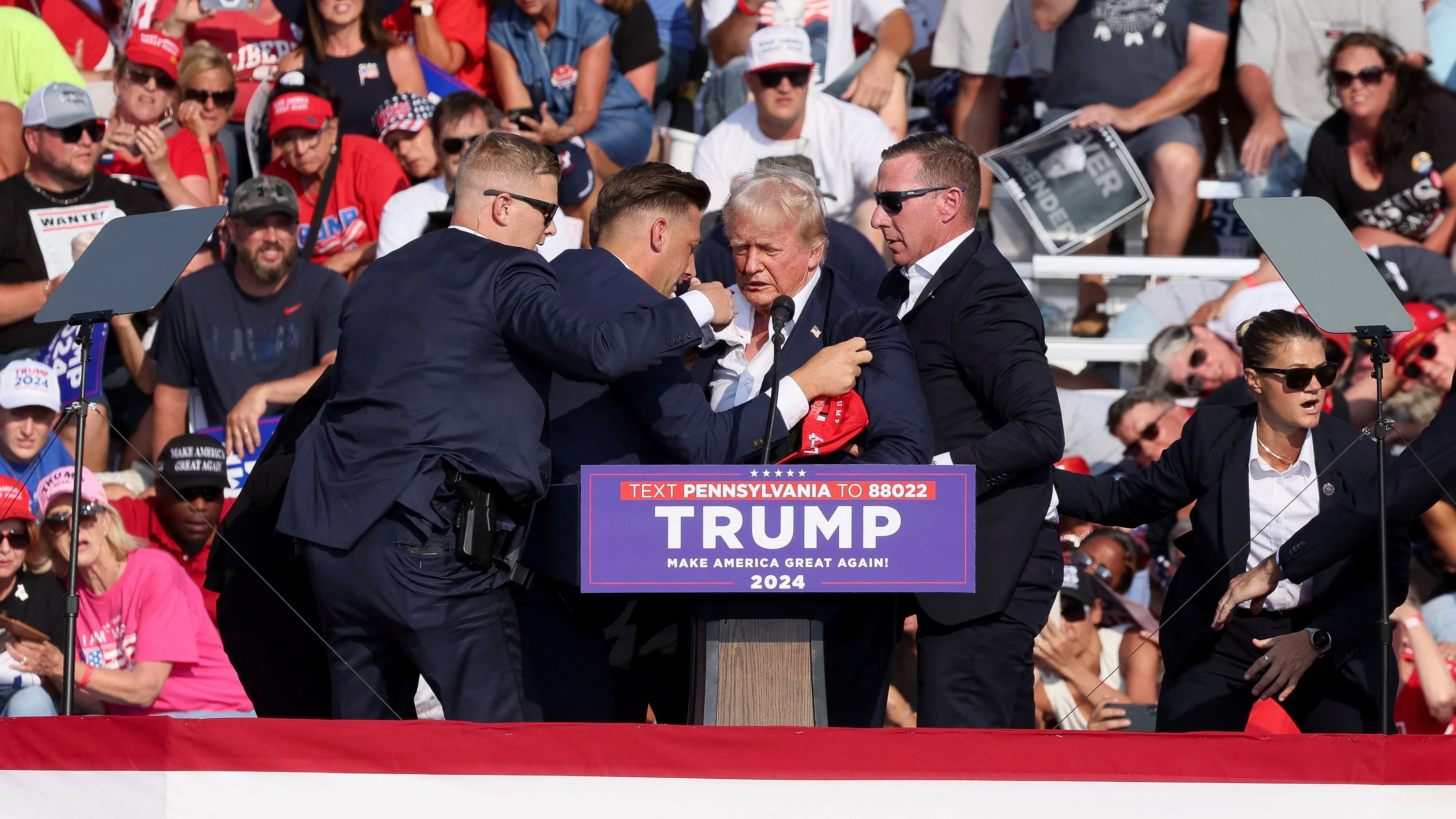 Republican presidential candidate and former U.S. President Donald Trump is assisted by U.S. Secret Service personnel after he was shot in the right ear during a campaign rally at the Butler Farm Show in Butler, Pennsylvania, U.S., July 13, 2024. REUTERS/Brendan McDermi