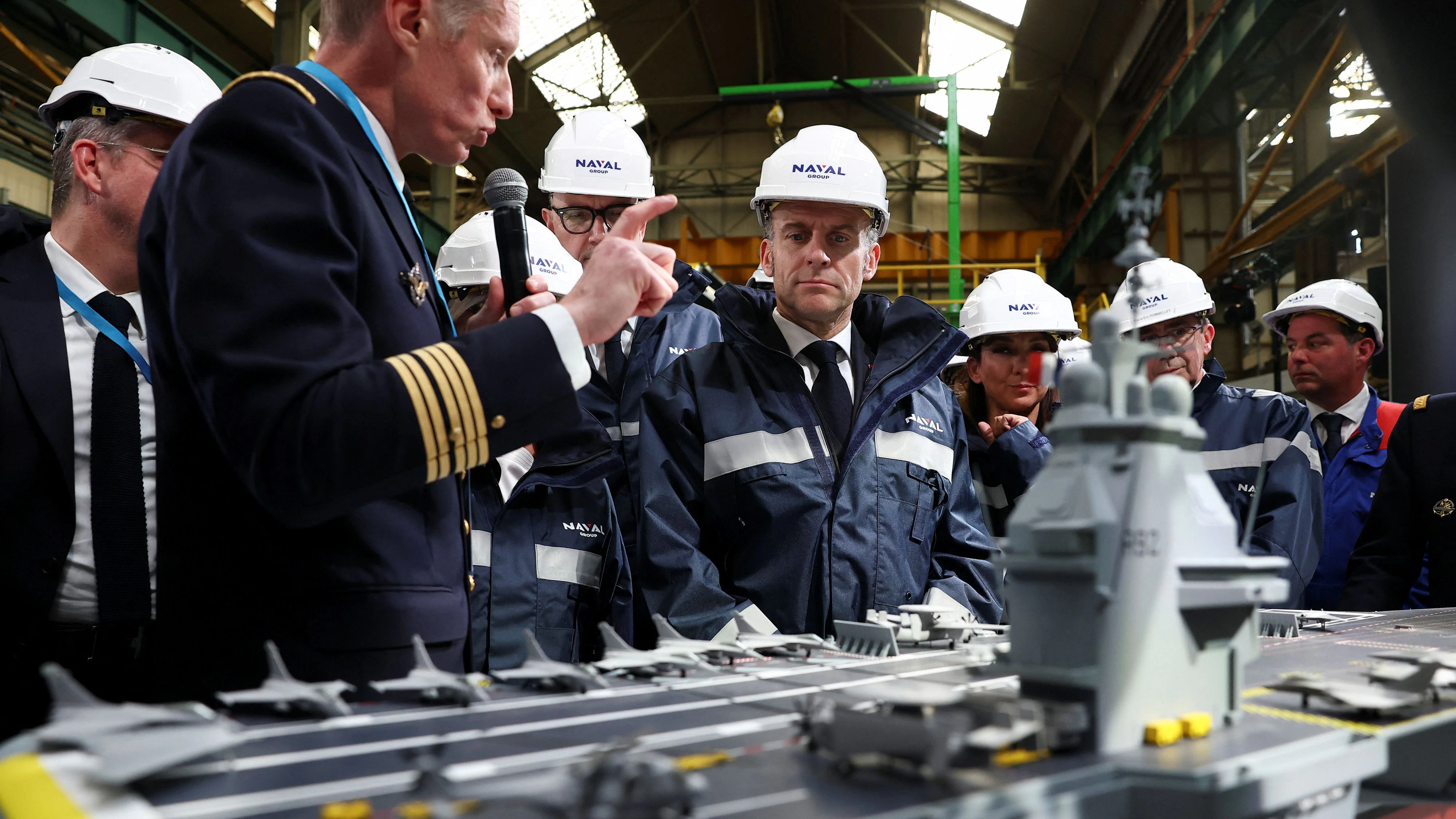 Frankreichs Präsident Macron (Mitte) lässt sich bei der Besichtigung einer Werft das Modell für den neuen französischen Flugzeugträger zeigen, dessen Bau im März 2026 begonnen hat.