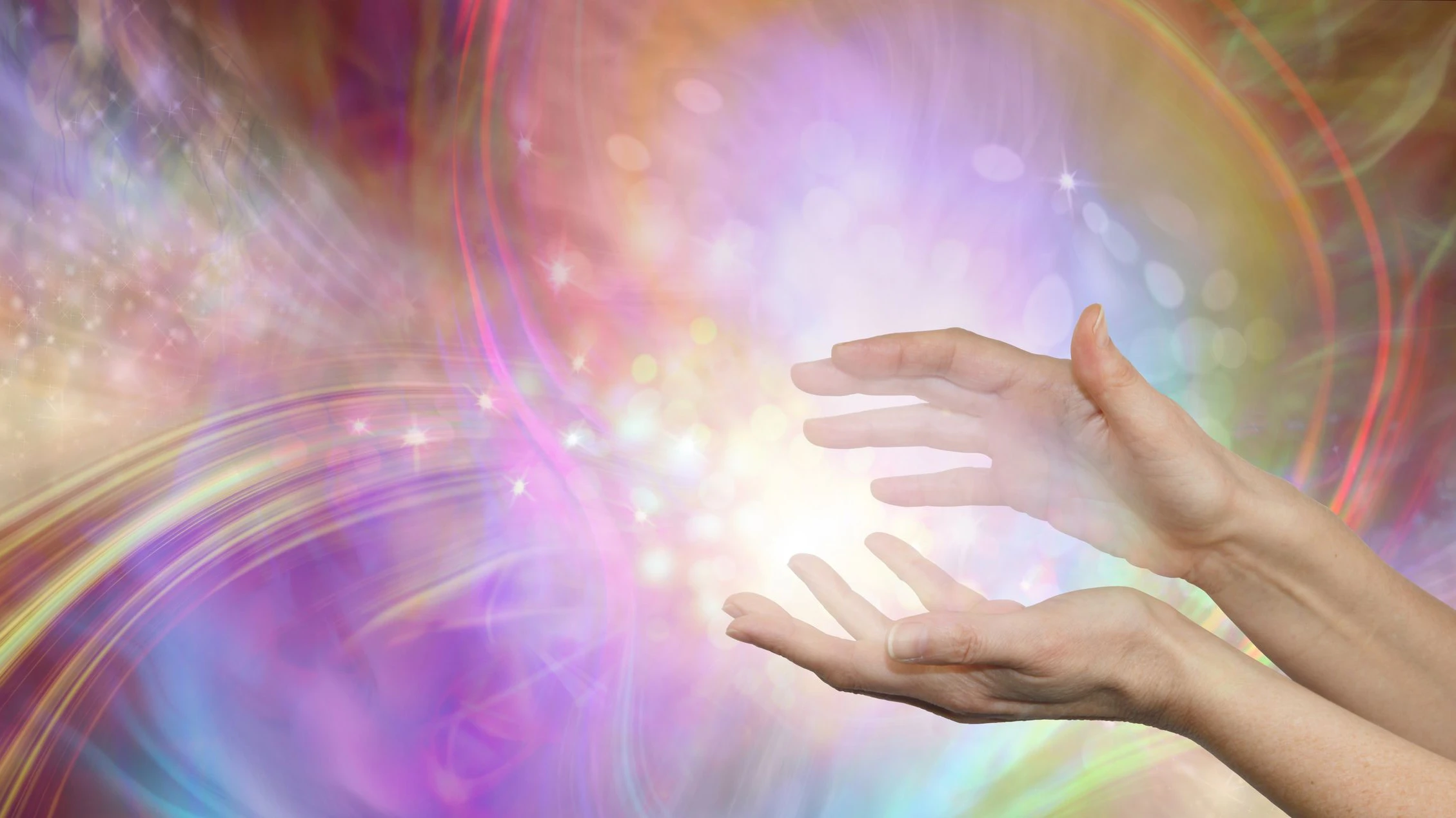female cupped hands with white energy formation flowing outwards, sparkles and warm  colours flowing in all directions with copy space