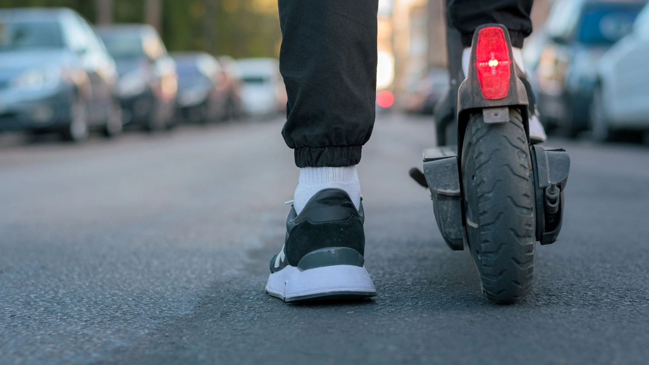 Close-up of a man riding an electric scooter on a street. Ground view