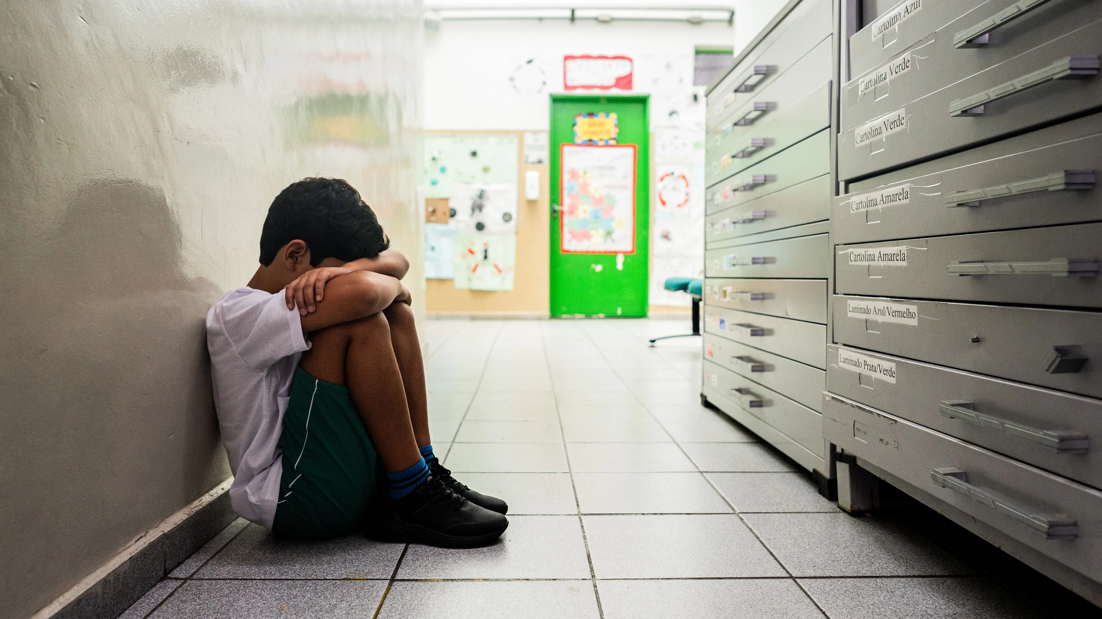 Sad child boy sitting on ground at school