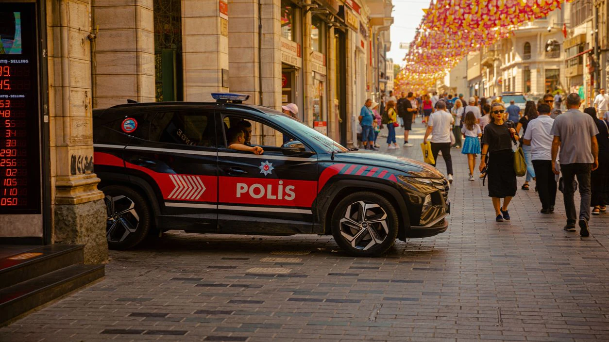Police patrol car stationed along Istiklal Street in Istanbul, surrounded by pedestrians and vibrant city life. The scene captures urban security and daily activity in Turkey’s most famous shopping and cultural avenue. Ideal for editorial use, news coverage, and cultural storytelling.