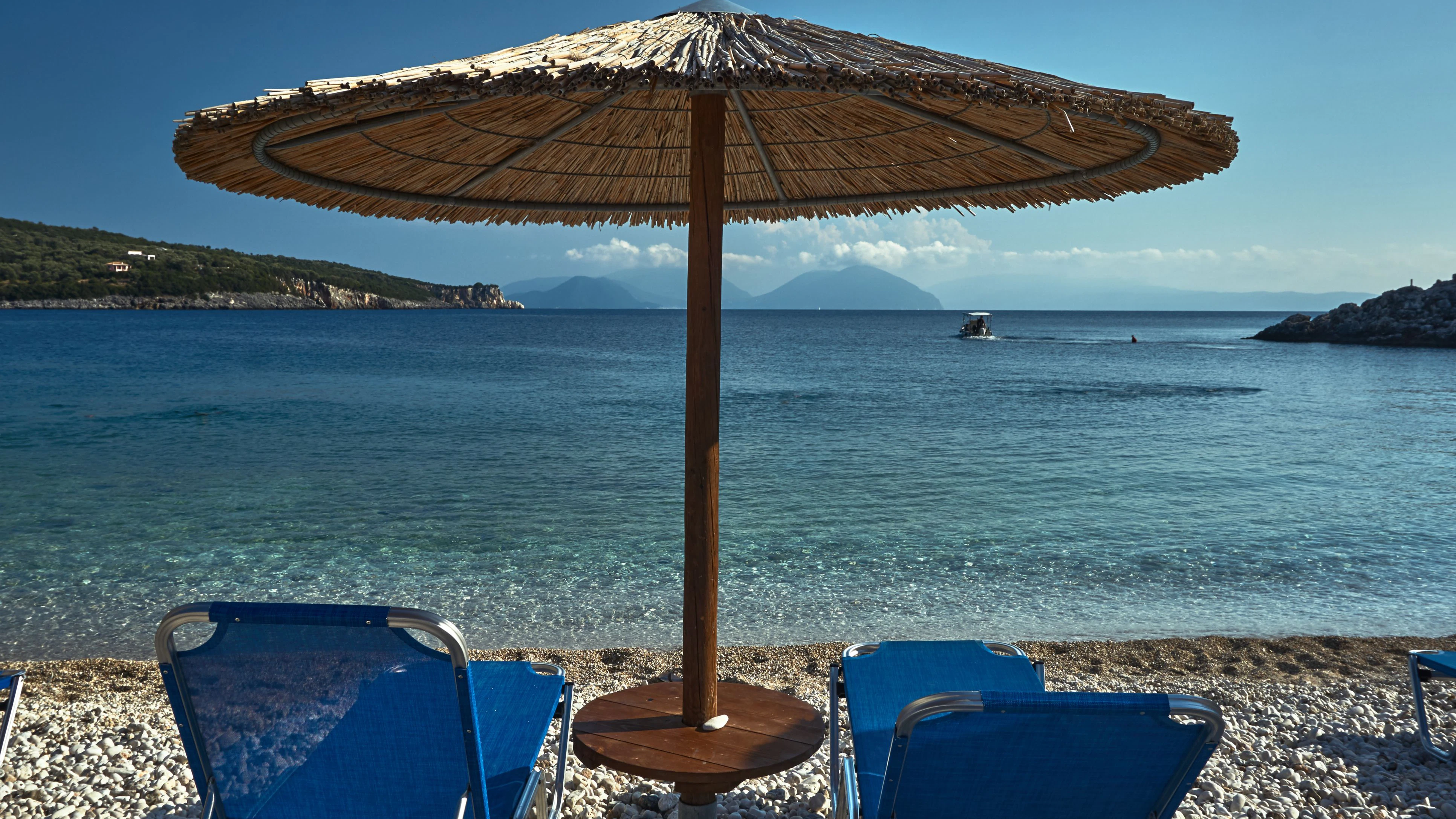 A straw parasol on a rocky beach on the Greek island of Lefkada