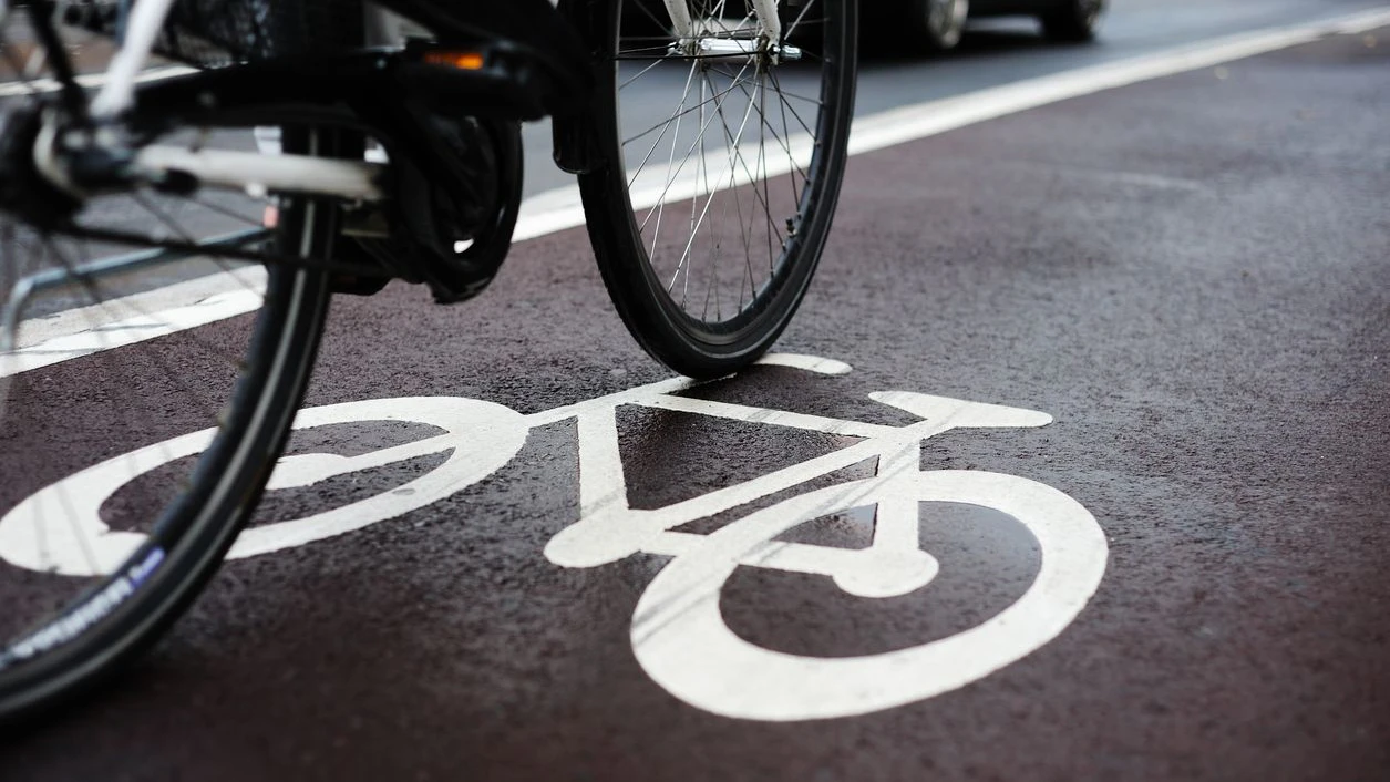 Bike lane on a rainy day. Sign for bicycle painted on the asphalt. Car and traffic in background. Dividing line, diminishing perspective. 