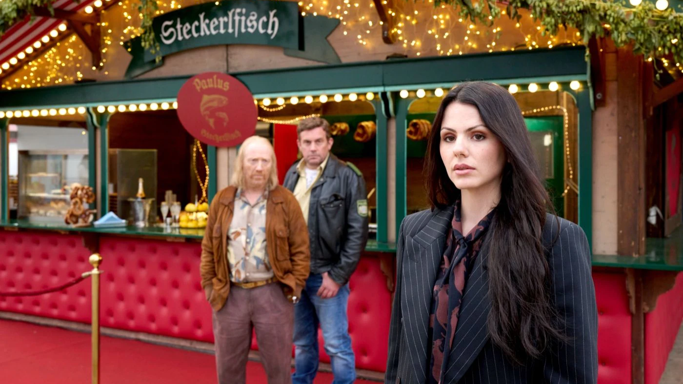 Rudi Birkenberger (Simon Schwarz) und Franz Eberhofer (Sebastian Bezzel) statten der Erbin des Steckerlfisch-Imperiums, Tessa Paulus (Ruby O. Fee), einen Besuch ab.