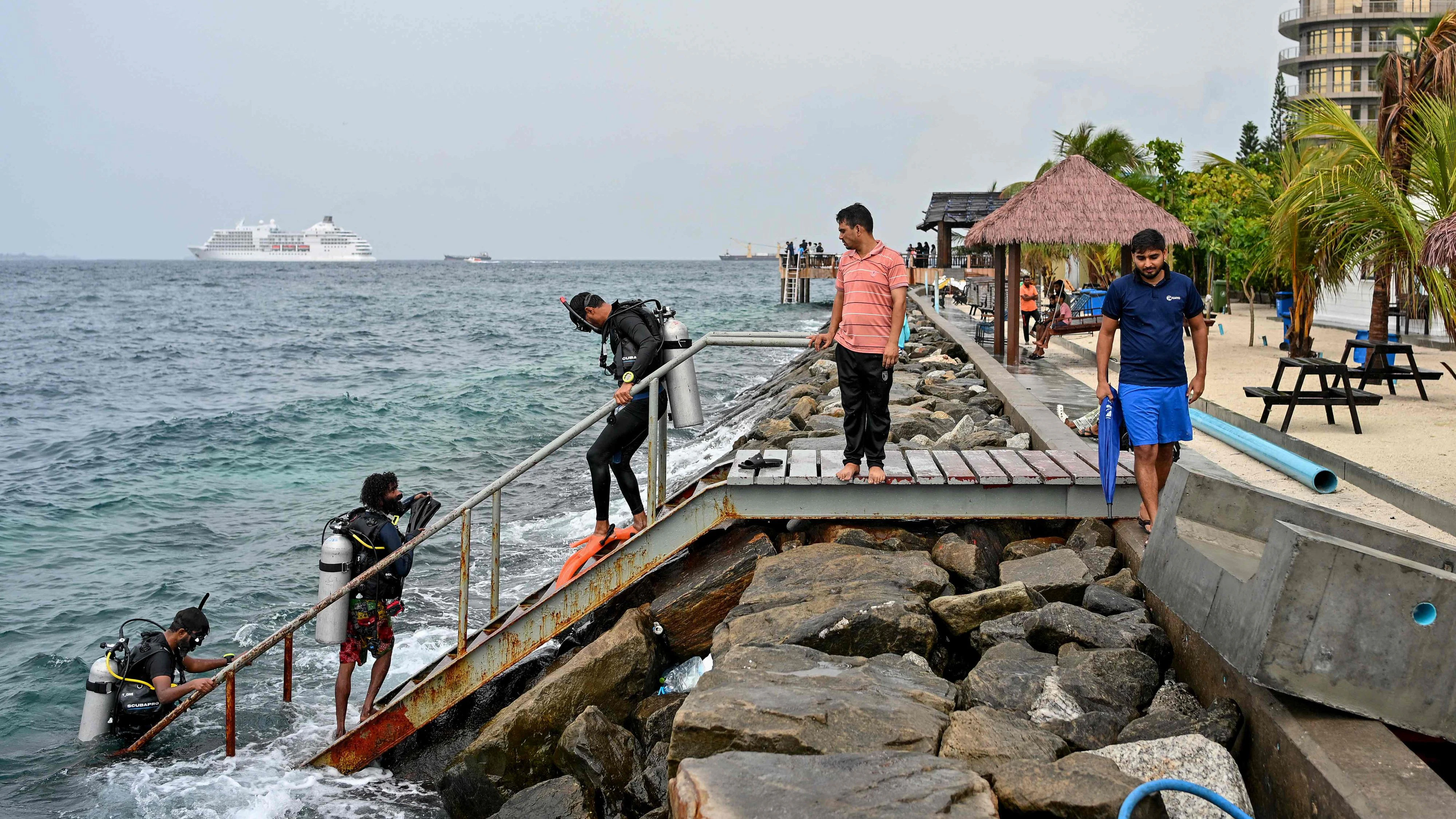 A tourist, along with guides, returns after an open-water diving session near Rasfannu Beach in Malé on May 15, 2026. Rescue teams in the Indian Ocean archipelago of the Maldives searched for a second day on May 15 for the bodies of four missing Italians following the country's deadliest diving accident, officials said. (Photo by Mohamed Afrah / AFP)