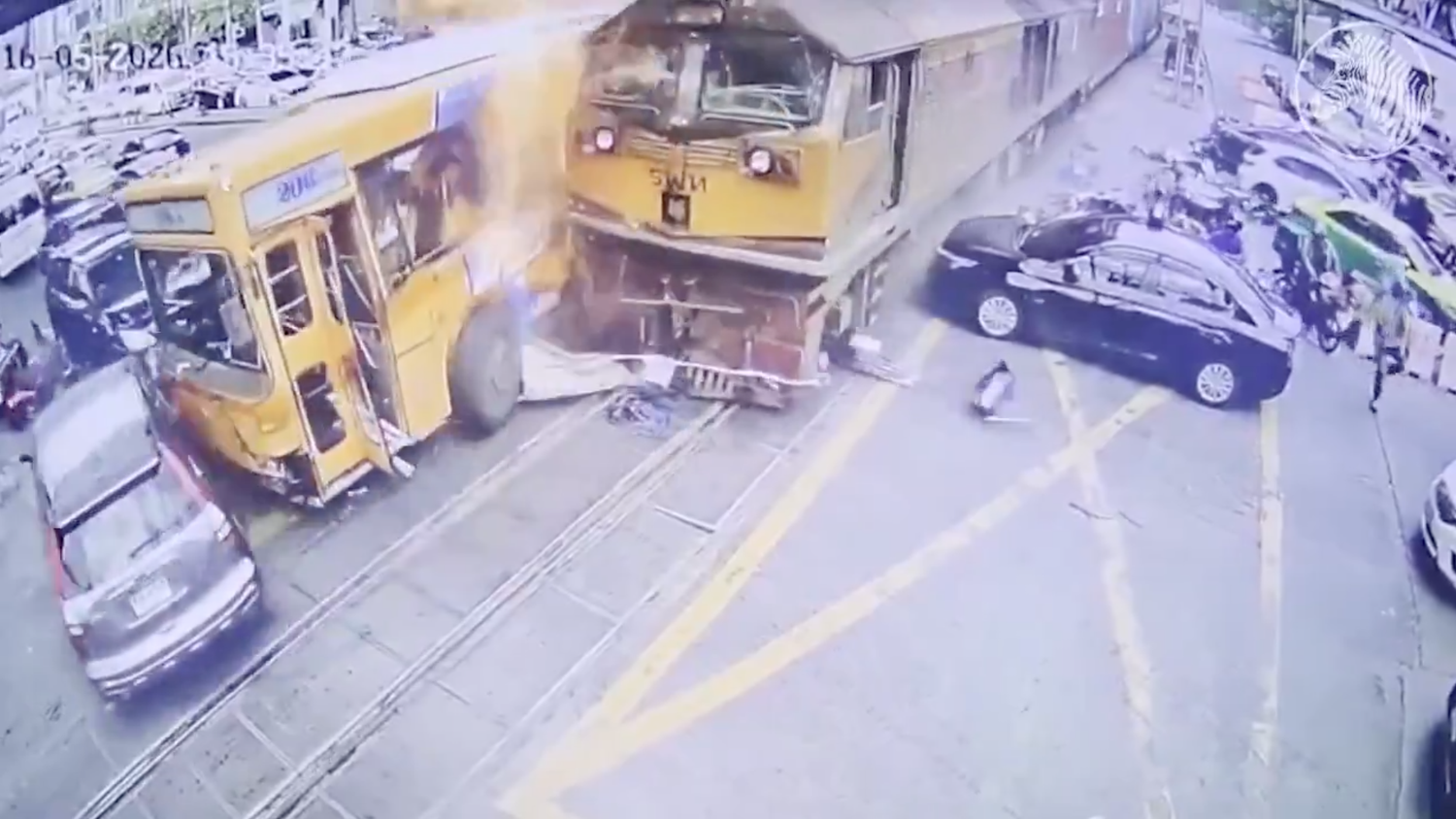 Überwachungsbilder zeigen, wie der Zug in langsamem Tempo die Fahrzeuge auf einer vielbefahrenen Straße im Zentrum von Bangkok zur Seite schiebt, wobei der Bus in Flammen aufgeht.