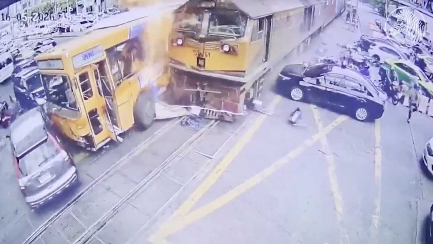 Überwachungsbilder zeigen, wie der Zug in langsamem Tempo die Fahrzeuge auf einer vielbefahrenen Straße im Zentrum von Bangkok zur Seite schiebt, wobei der Bus in Flammen aufgeht.