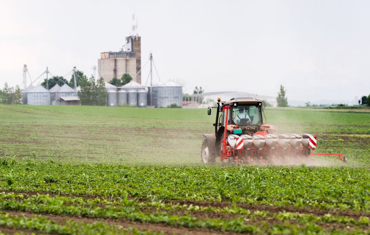 Farmer with tractor seeding  crops at agricultural field