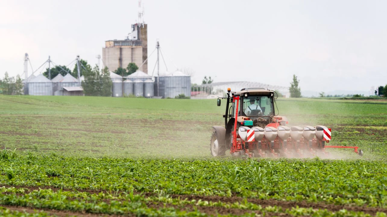 Farmer with tractor seeding  crops at agricultural field