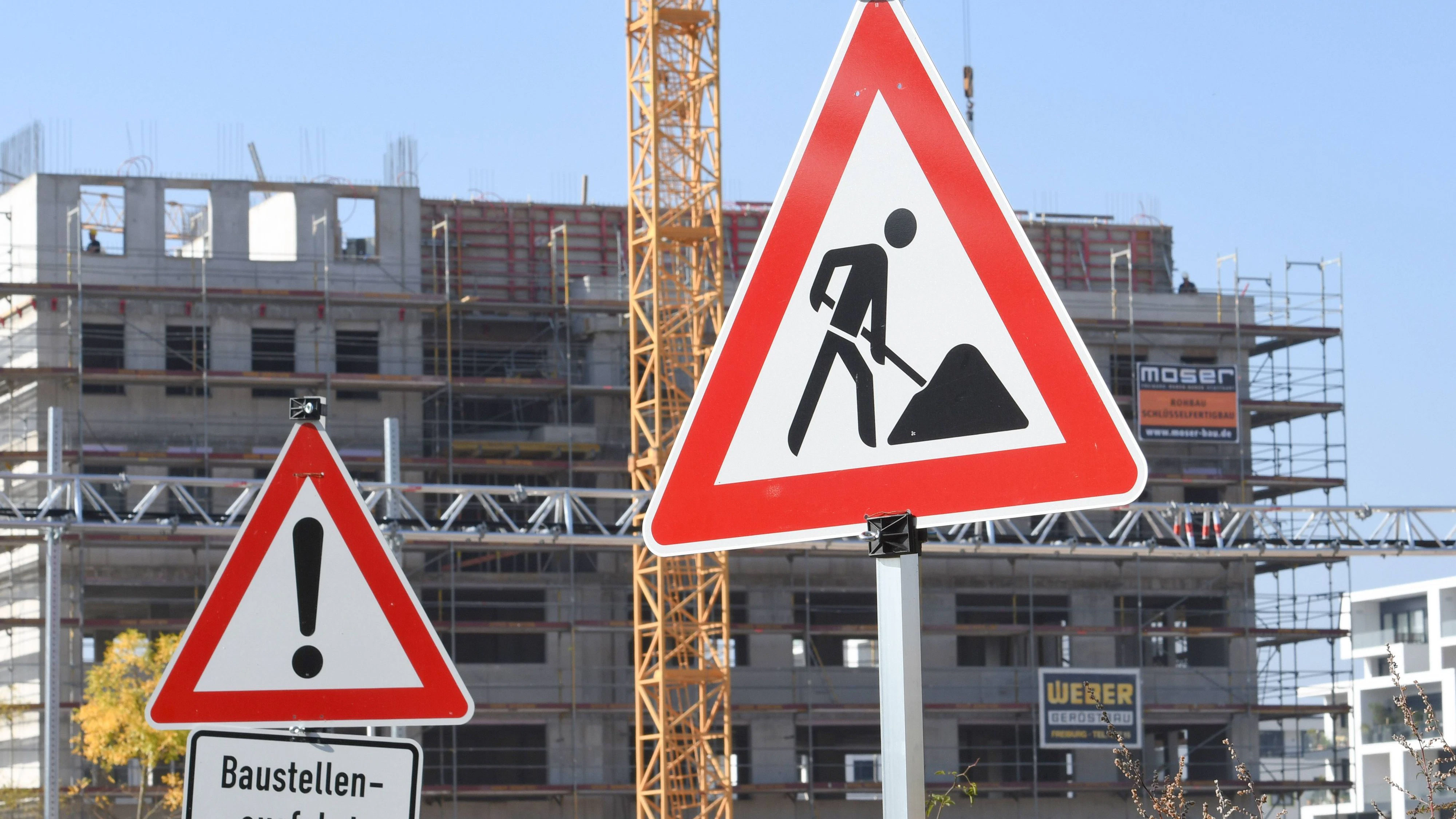 Warnschilder: Baustelle und Baustellenausfahrtin einem Neubauviertel in Freiburg. Überall in Deutschland mangelt es an bezahlbarem Wohnraum. *** Warning signs construction site and construction site exit in a new building district in Freiburg Everywhere in Germany there is a lack of affordable housing  