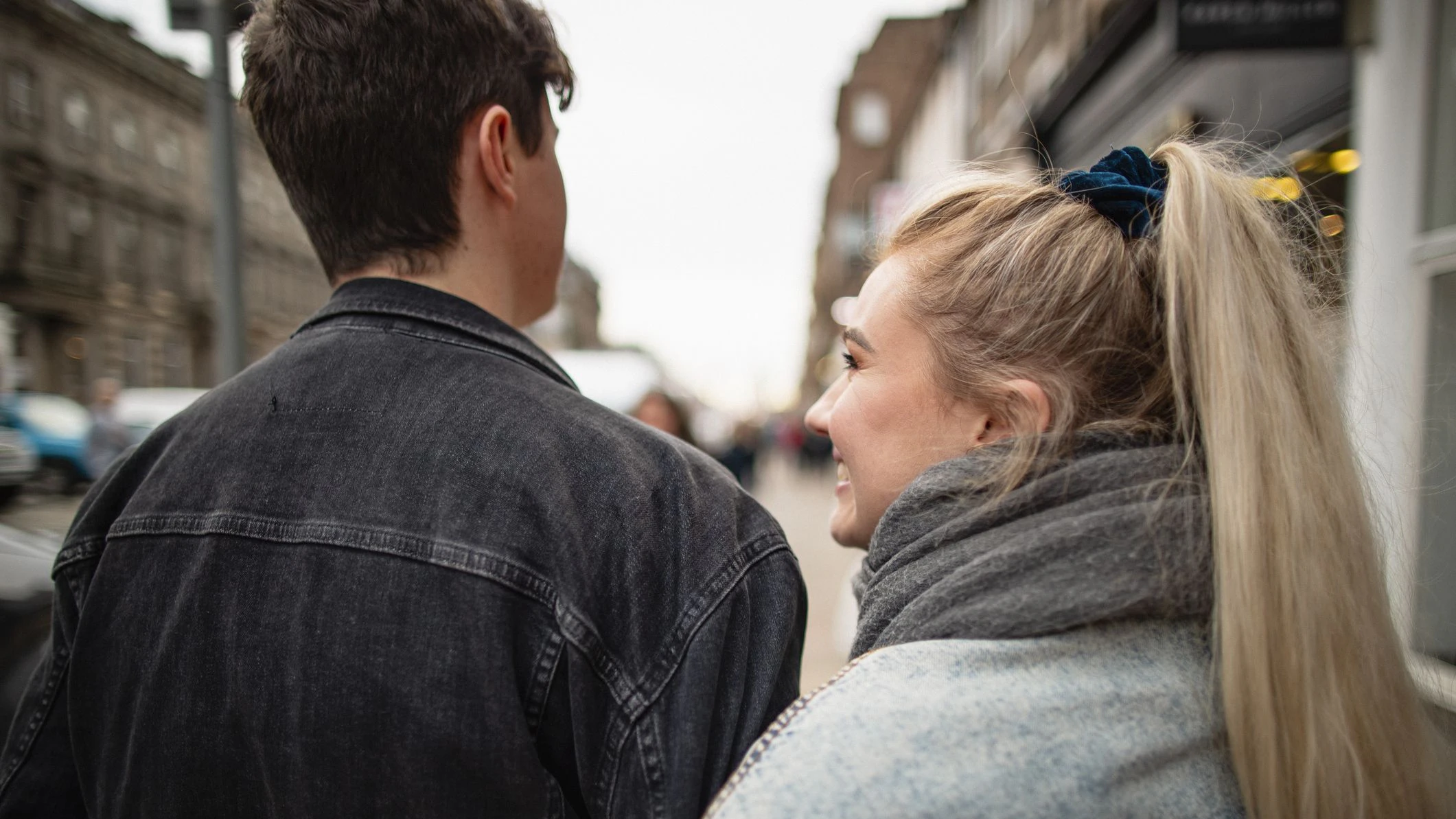 Rückansicht eines jungen Paares, das durch die Straßen von Edinburgh geht.