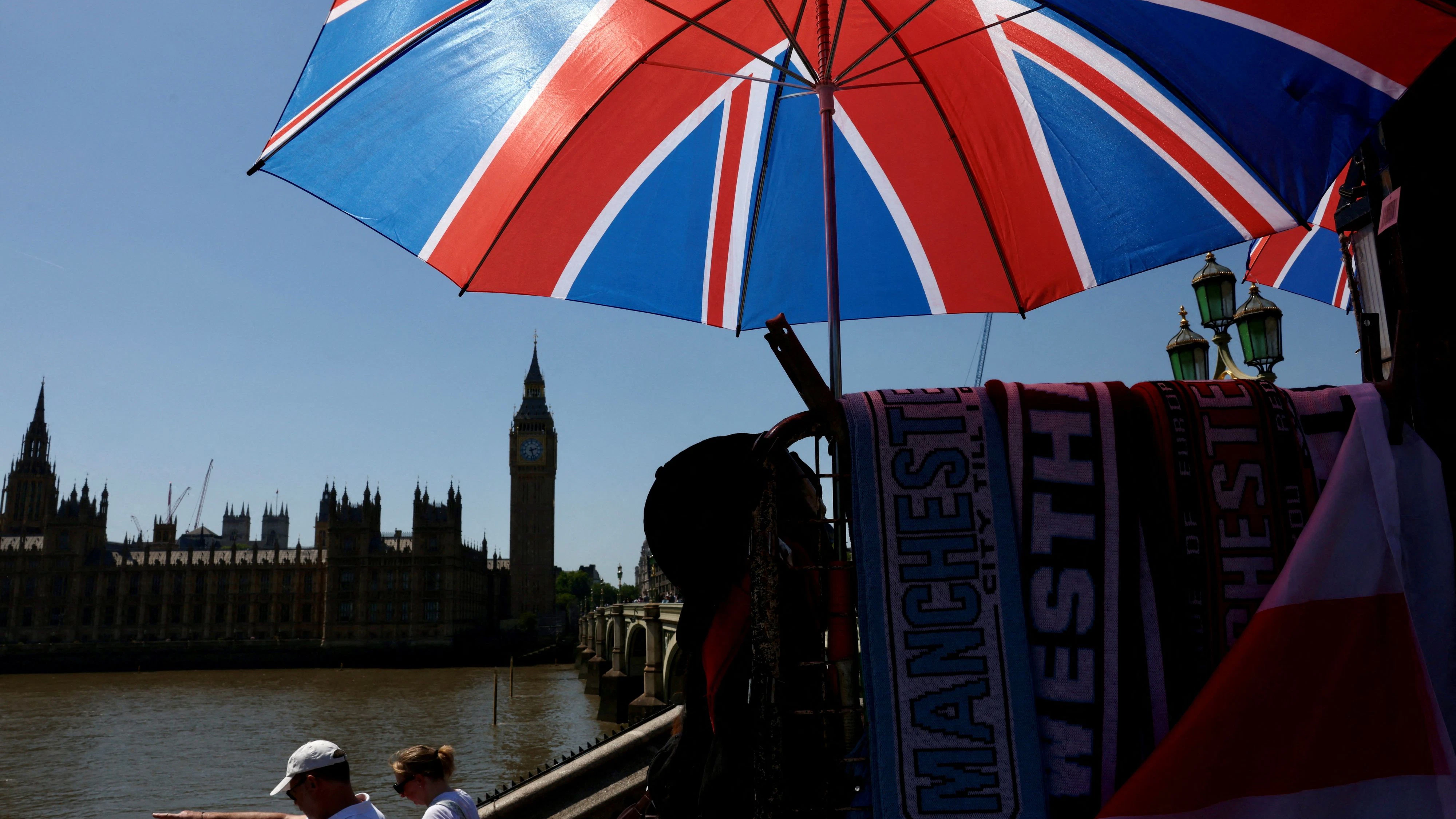 Tourists walk past a souvenir vendor in front of Big Ben during a heatwave as the UK experienced record temperatures for the month of May in London, Britain, May 25, 2026. REUTERS/Kevin Coombs     TPX IMAGES OF THE DAY     