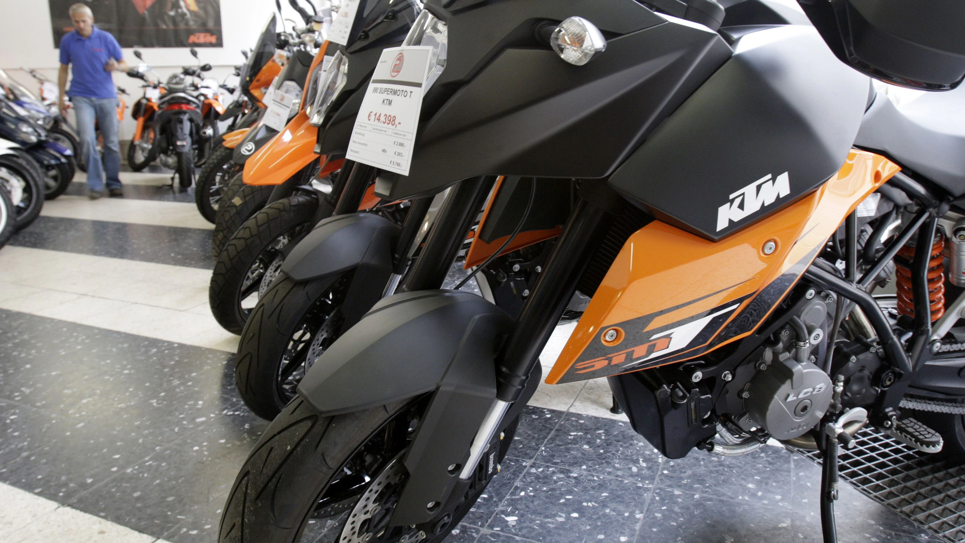 A man walks through a showroom with motorcycles of Upper Austrian manufacturer KTM in Vienna June 15, 2009. The provincial government of Upper Austria will grant financial guarantees to KTM after the company had to reduce production due to poor sales, a spokesman of the Upper Austrian government said on Monday.   REUTERS/Herwig Prammer  (AUSTRIA EMPLOYMENT BUSINESS TRANSPORT)