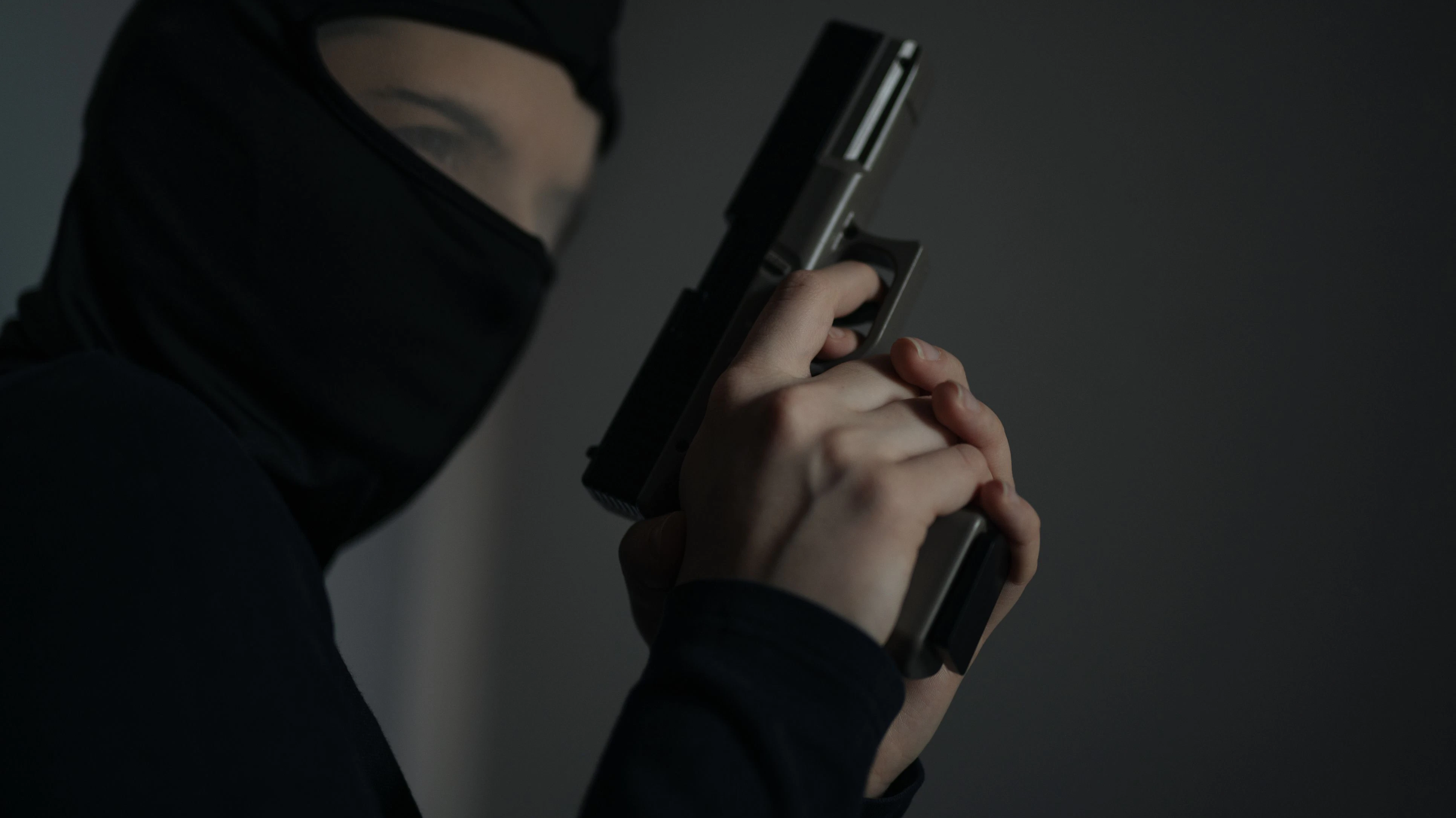 Female armed thief with black mask and pistol breaks into a house.