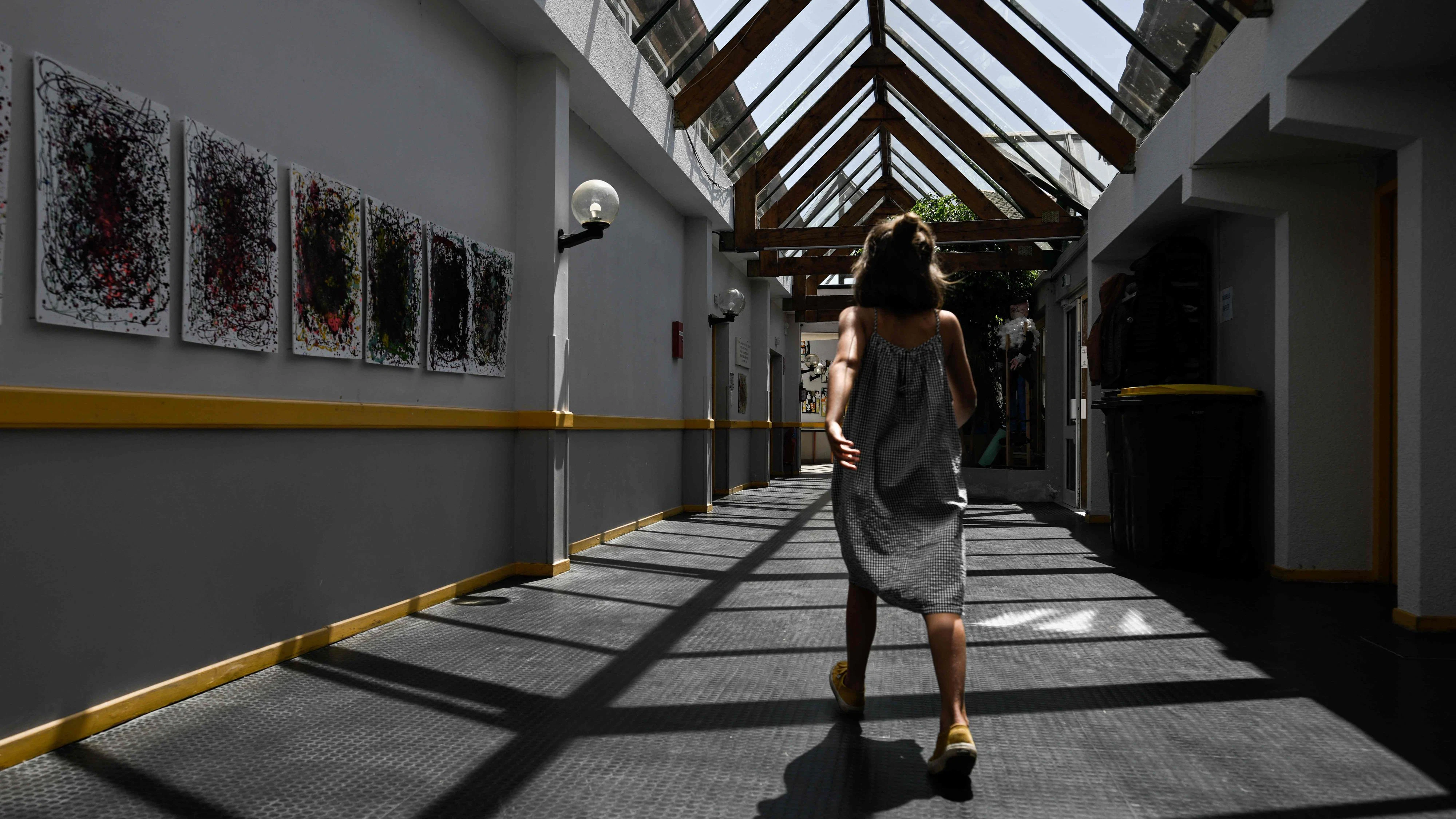 TOPSHOT - A child walks along the glass-roofed corridor of the Isle Verte primary school which closes its doors on May 28 and 29 afternoon after a heatwave pushed temperatures up to 53°C at the beginning of the week, in Soustons, south-western France, on May 28, 2026. Western Europe faced another day of record-breaking temperatures as a heatwave pushed the mercury well above normal levels for May. A so-called "heat dome" of warm air from northern Africa trapped under a high-pressure system over western Europe is behind the sort of heat not usually seen until high summer. (Photo by Philippe LOPEZ / AFP)