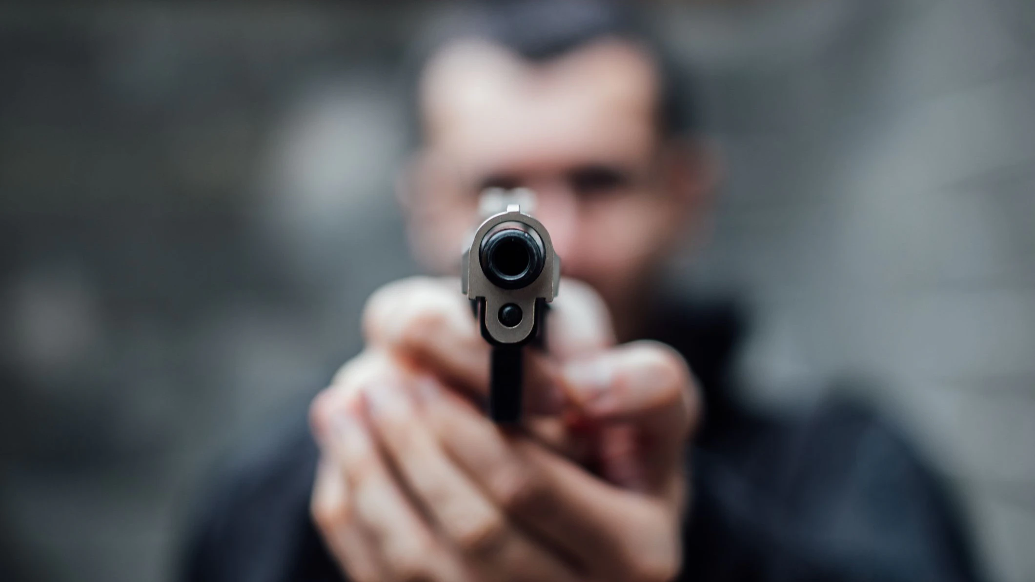 A man is pointing a gun directly at the lens.