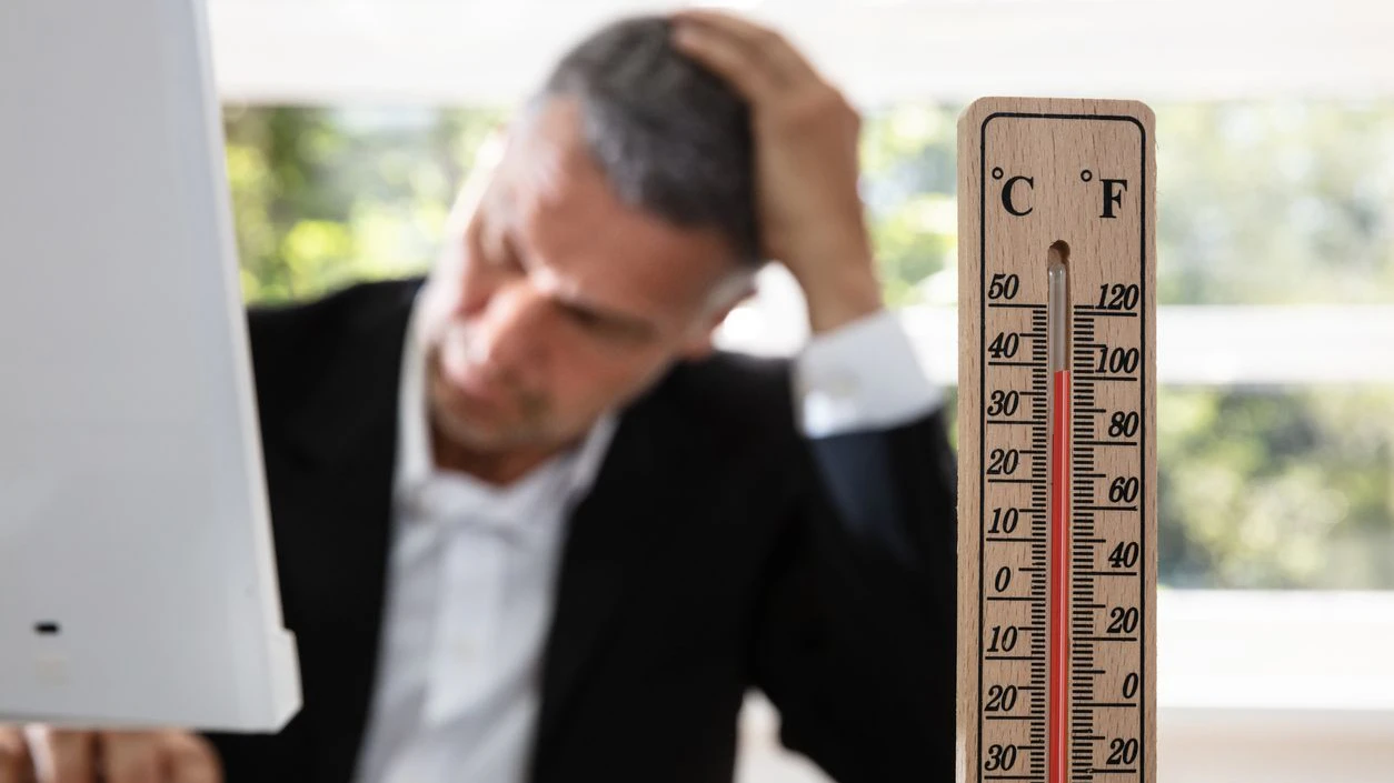 Thermometer In Front Of Businessman Working During Hot Weather In The Office